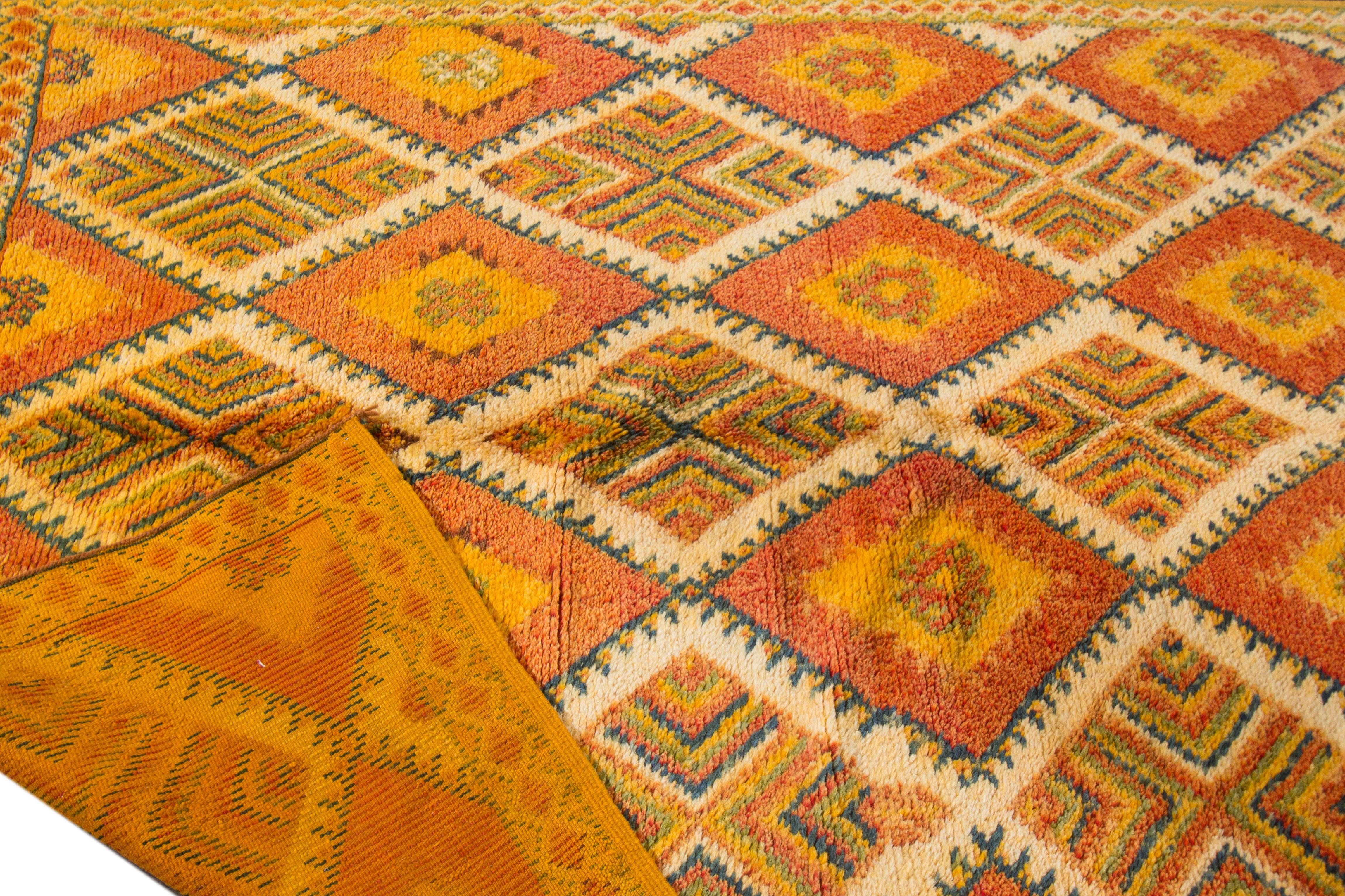 Schöner marokkanischer handgeknüpfter Wollteppich im Vintage-Stil mit orangefarbenem Feld. Dieser marokkanische Teppich hat grüne, gelbe und blaue Akzente in einem prächtigen geometrischen Rautenmuster. 

Dieser Teppich misst 5' x 11'6