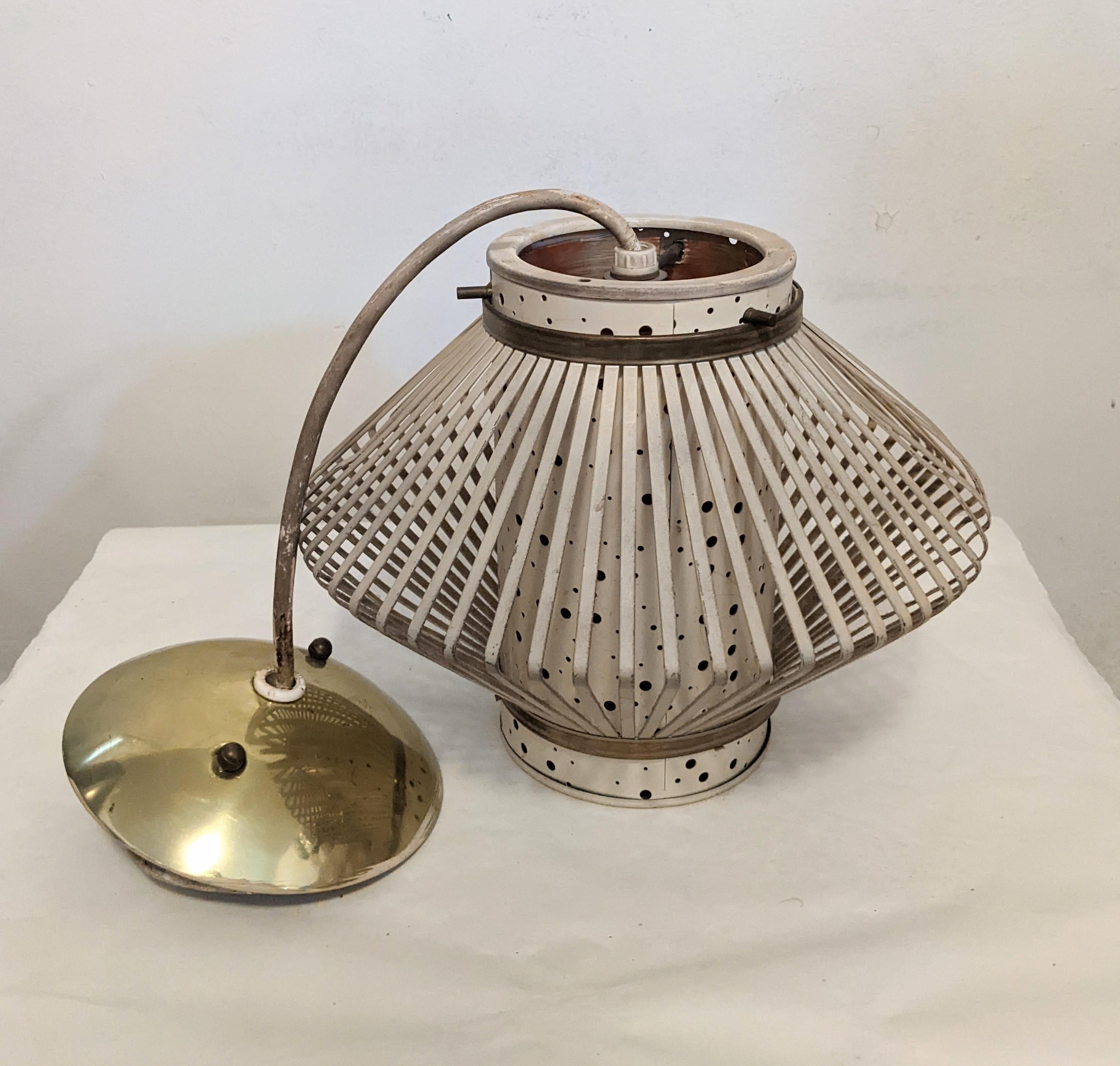 1950s Atomic style pendant lantern in enameled metal with a spun nylon interior in tones of oranges and yellow. When the fixture is lit, little dots of color emanate from within and light up a dark room. 
Fixture measures 12
