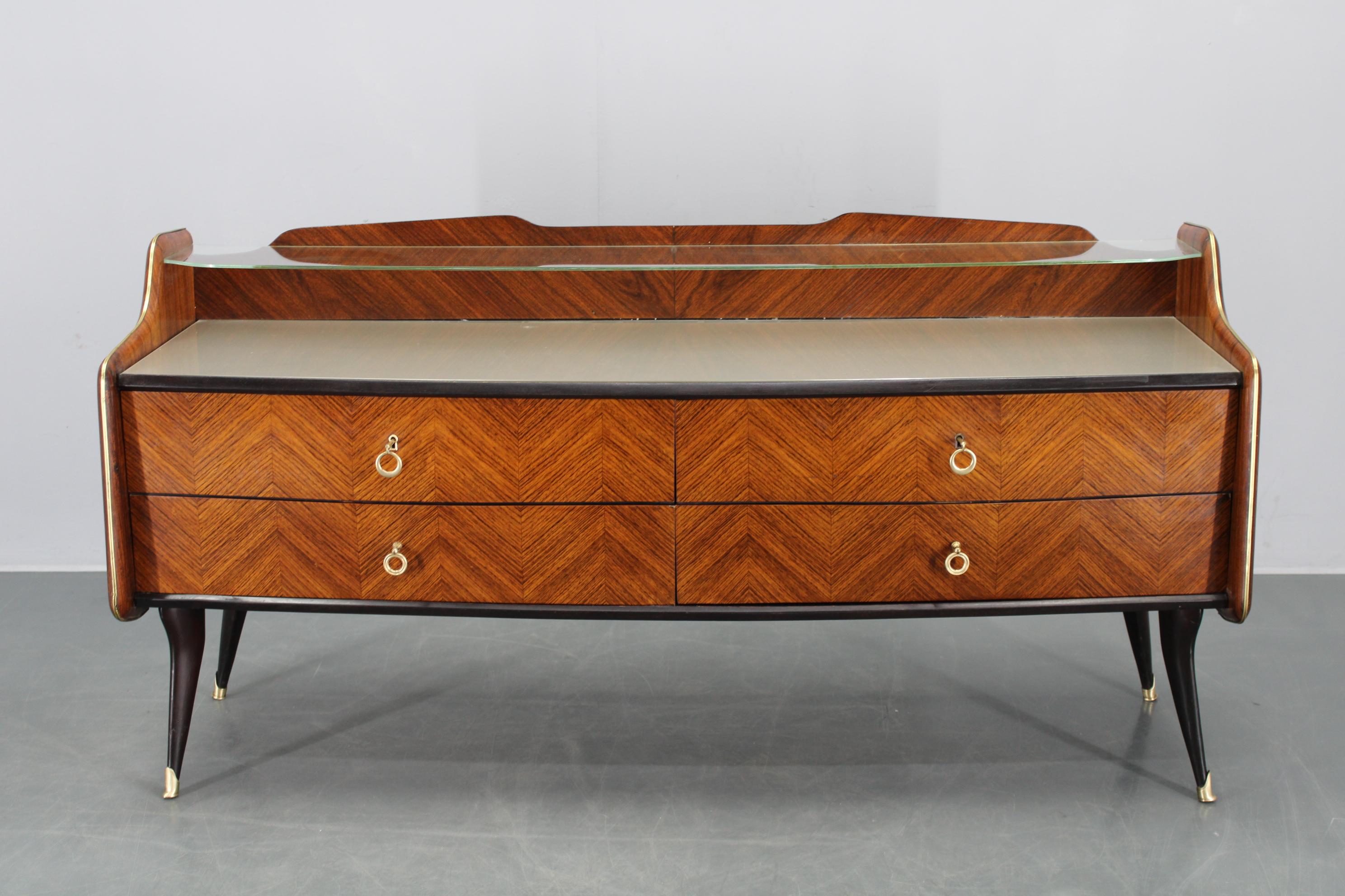 Aparador italiano de mediados de siglo fabricado en la década de 1950, con un característico diseño orgánico de cuatro cajones espaciosos, elegantes superficies chapadas y un esqueleto de madera maciza. La balda superior tiene un acabado de cristal,