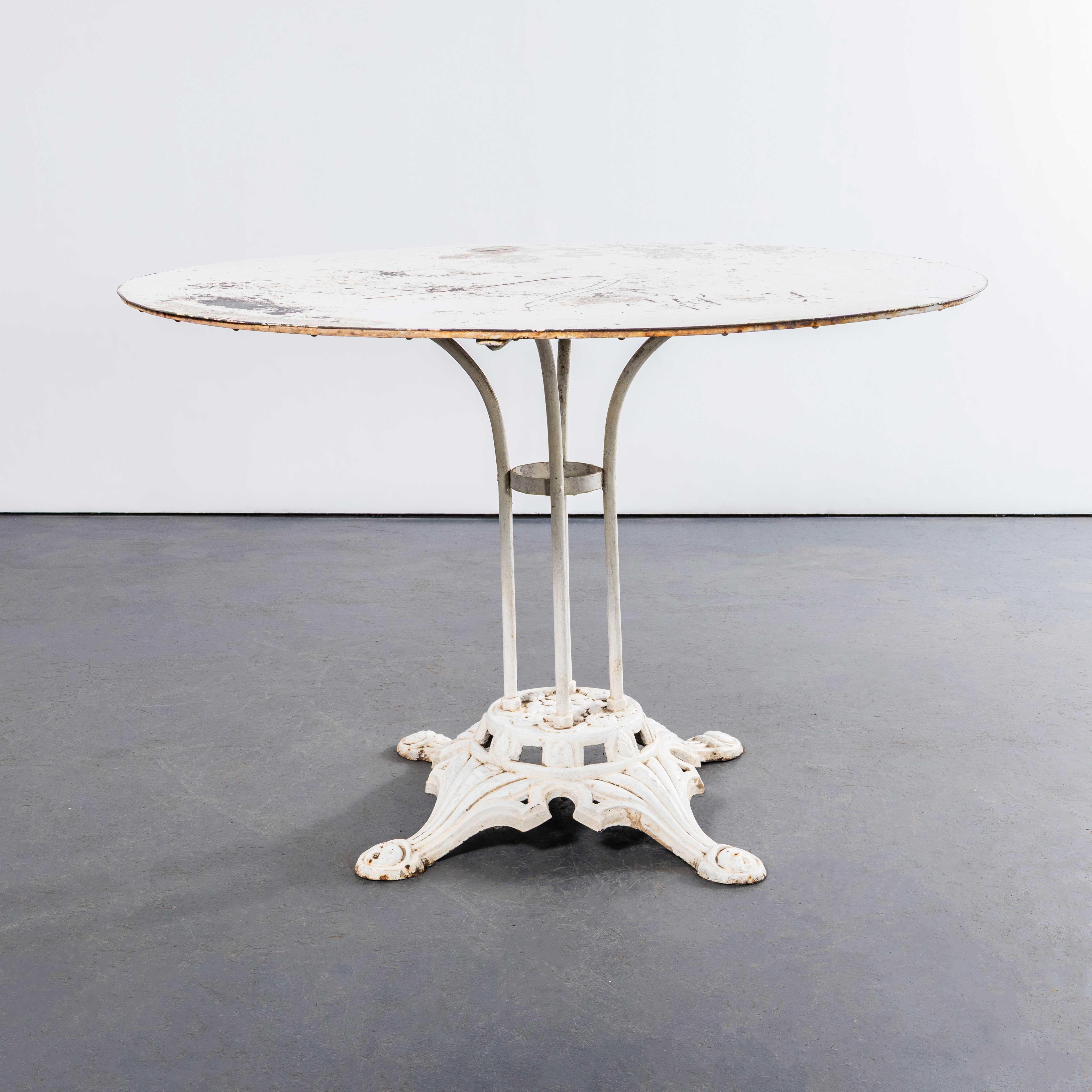 Mesa de comedor de exterior redonda francesa original de los años 50 - Blanca. Mesa clásica francesa con cuatro patas de barra maciza moldeadas a mano con un anillo central de apoyo remachado y delicados pies curvados sobre una base de metal fundido