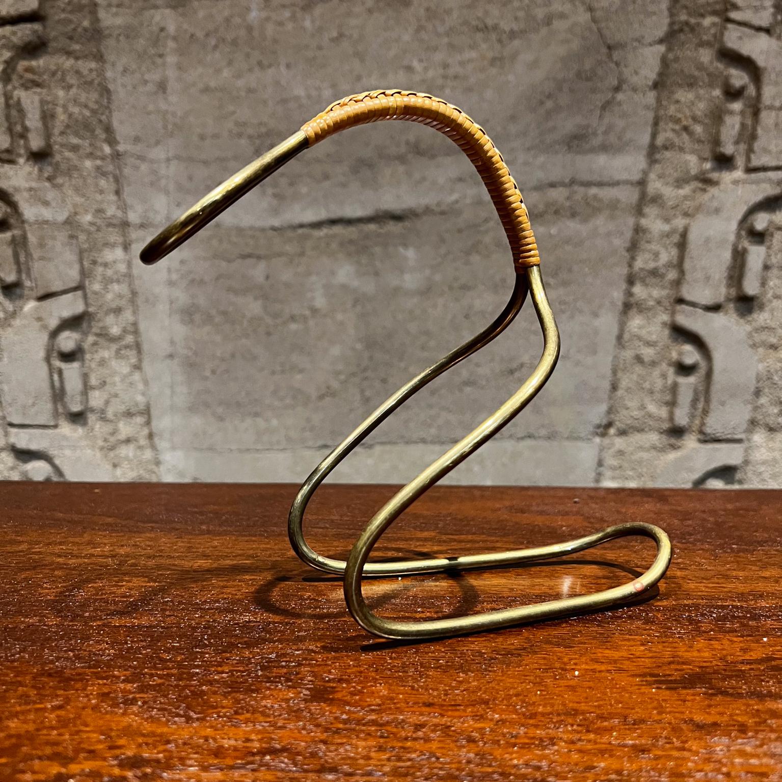 1950s Sculptural Wine Bottle Holder
In the style of Carl Auböck Austria
Marked Orop
Designed in Brass and wrapped Cane 
9 long x 8 tall x 3.75 w inches
Preowned original vintage condition.
Review images carefully.


