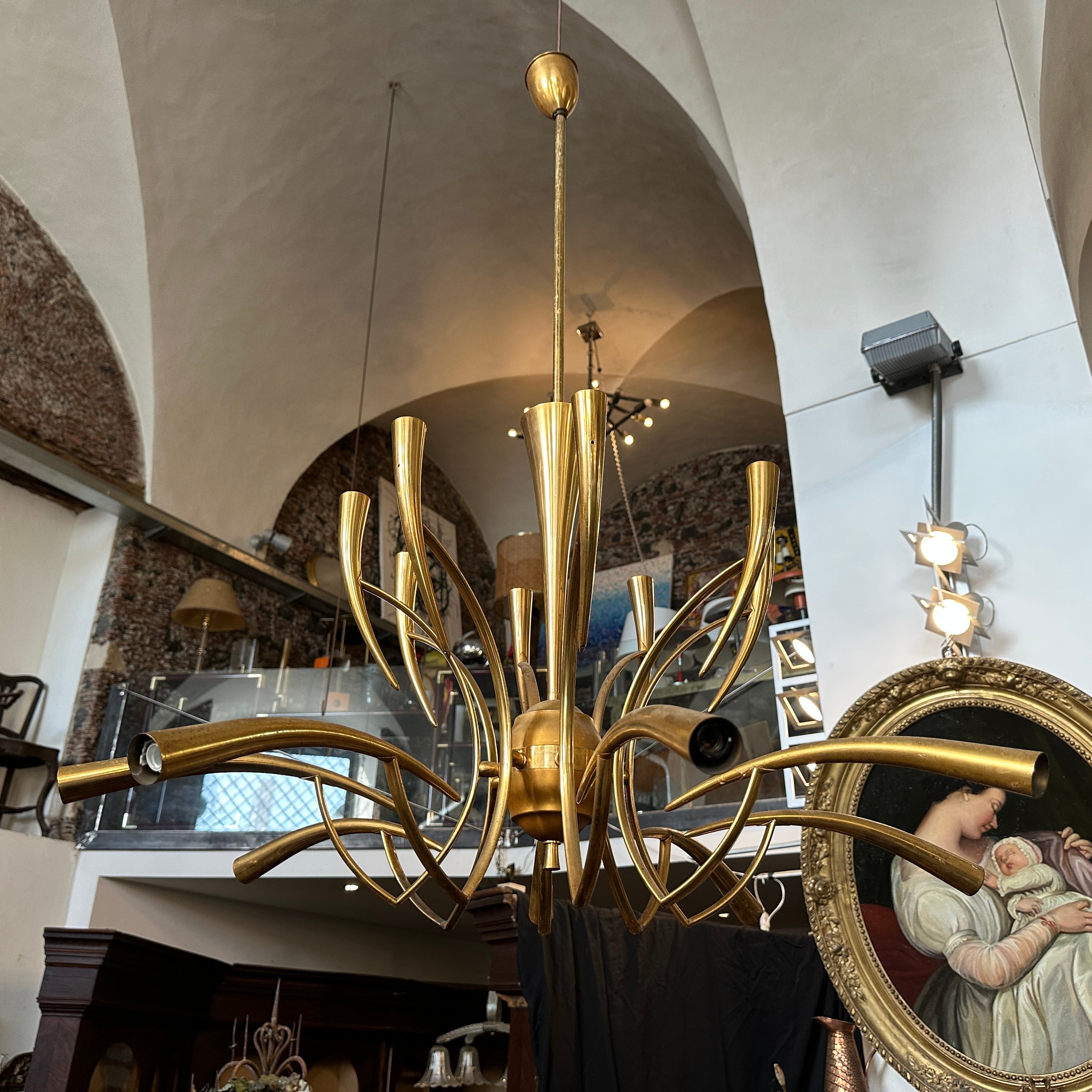 Ce magnifique lustre est un luminaire en laiton de style Mid-Century Modern des années 1950, conçu par Oscar Torlasco pour Lumi Milano. Elle présente un élégant design sculptural avec 16 bras gracieusement incurvés qui s'étendent vers l'extérieur à