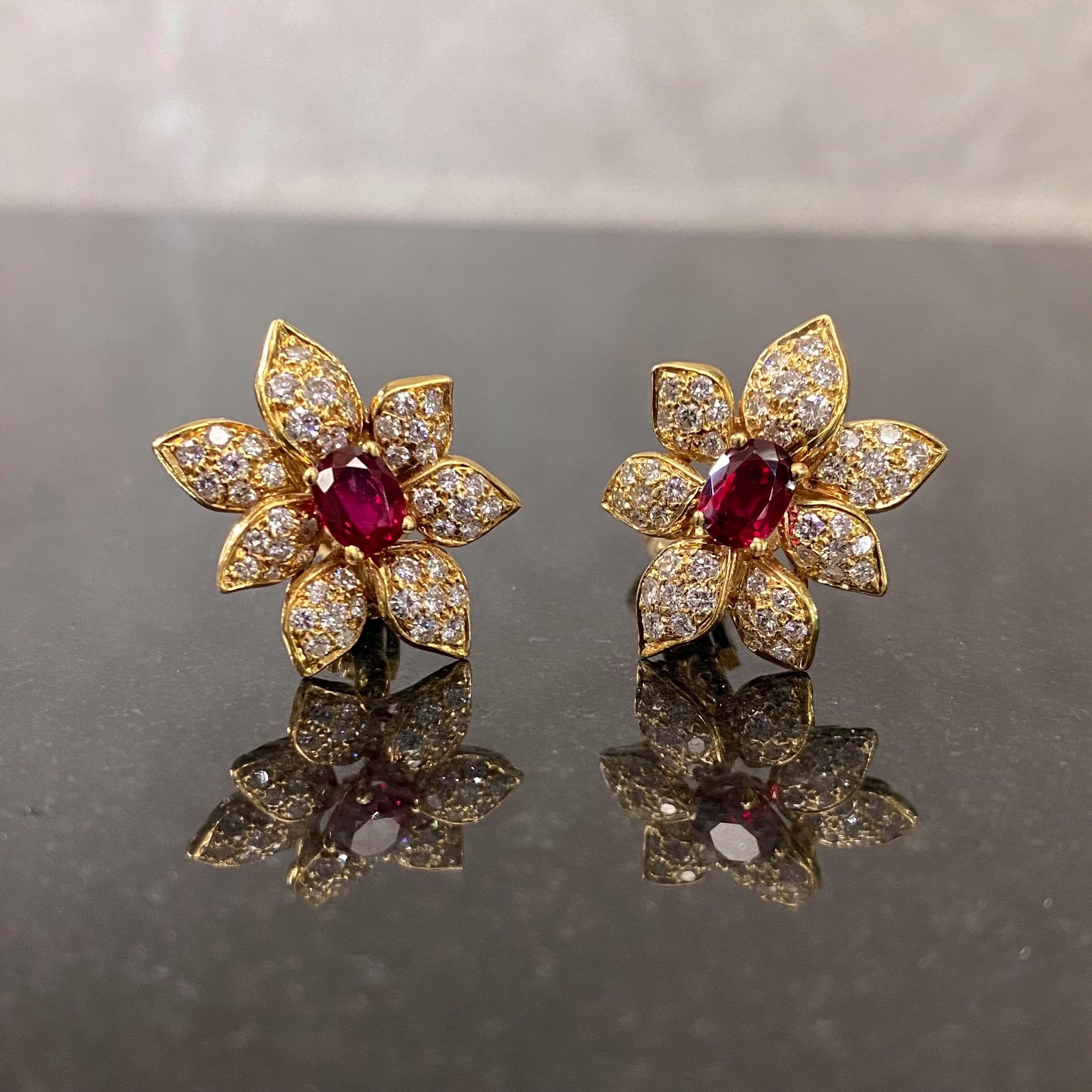A pair of oval mixed-cut ruby and round brilliant-cut diamond floral clip earrings in 18 karat yellow gold, French, 1950s. Each earring is modelled as a stylized lotus flower, with a deep red oval-shaped ruby claw-set to the center, the seven petals