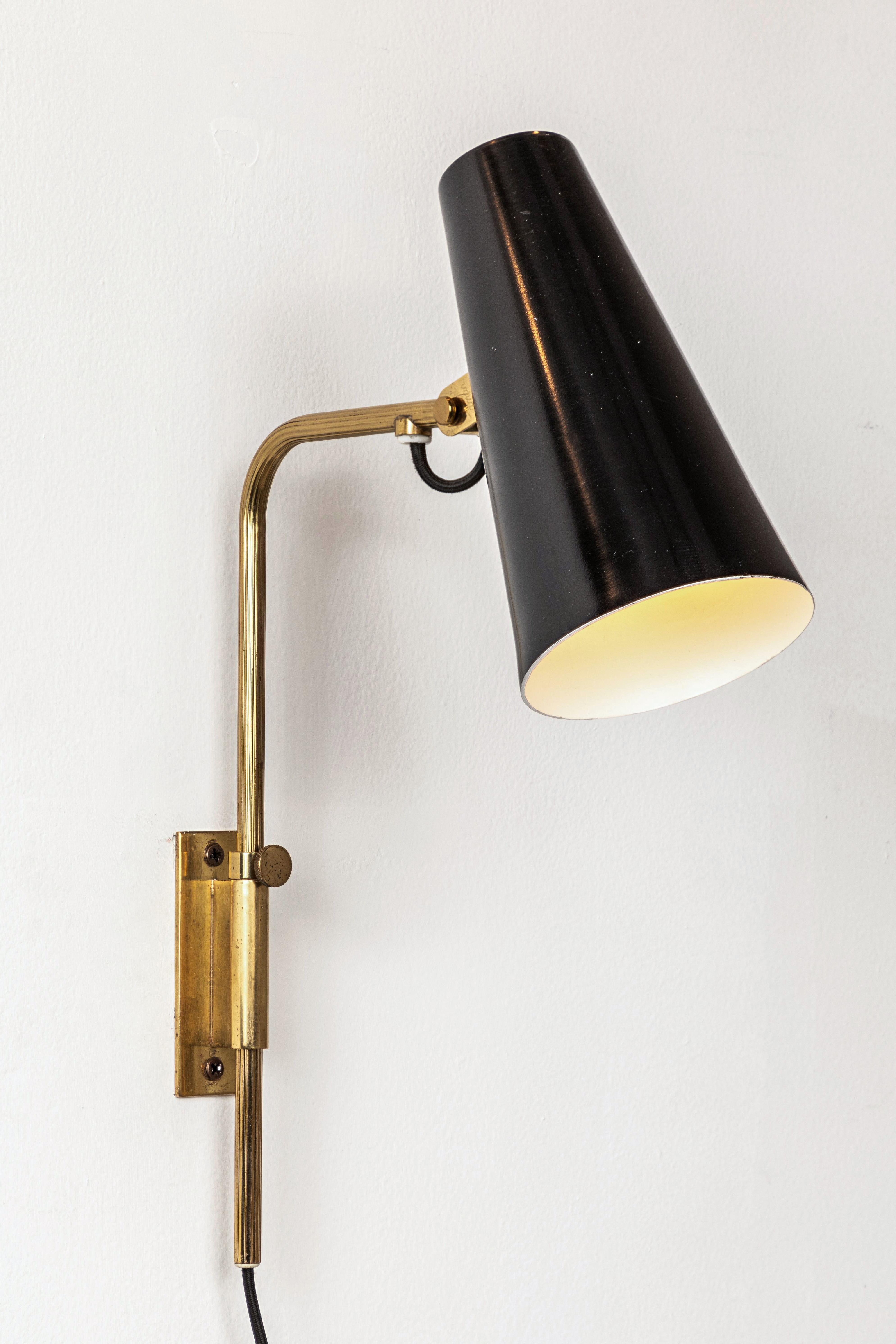 1950s Paavo Tynell 9459 wall lights for Taito OY. These rare and exceptionally refined wall lights are executed in white enameled steel and attractively patinated brass. Signed with impressed manufacturer's mark to shade of each example, circa 1950,