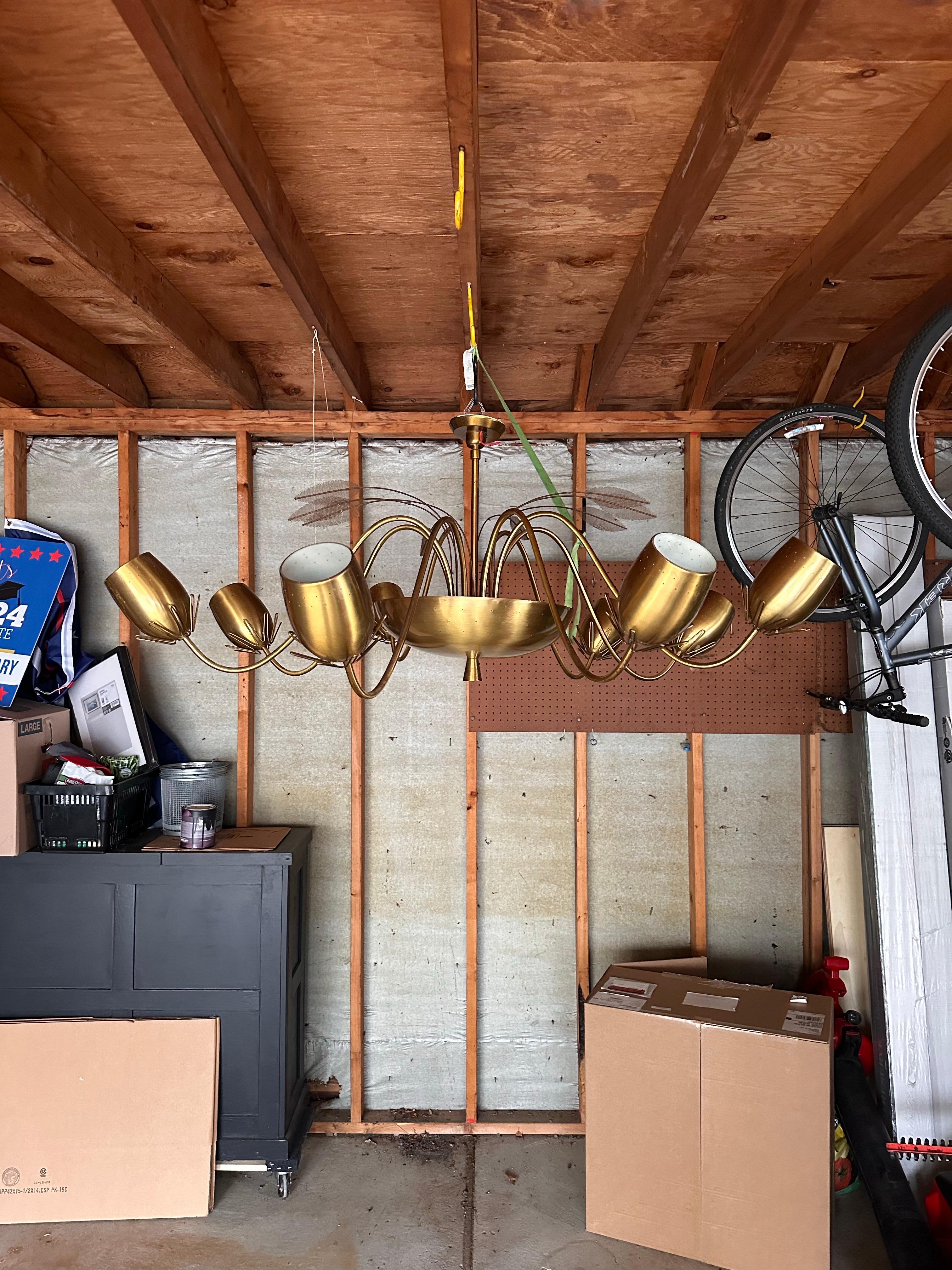 Nous avons le plaisir de vous proposer un exquis lustre à huit lumières attribué au célèbre designer finlandais Paavo Tynell en collaboration avec Lightolier, vers les années 1950.  Le lustre comporte huit bras en laiton élégamment courbés qui
