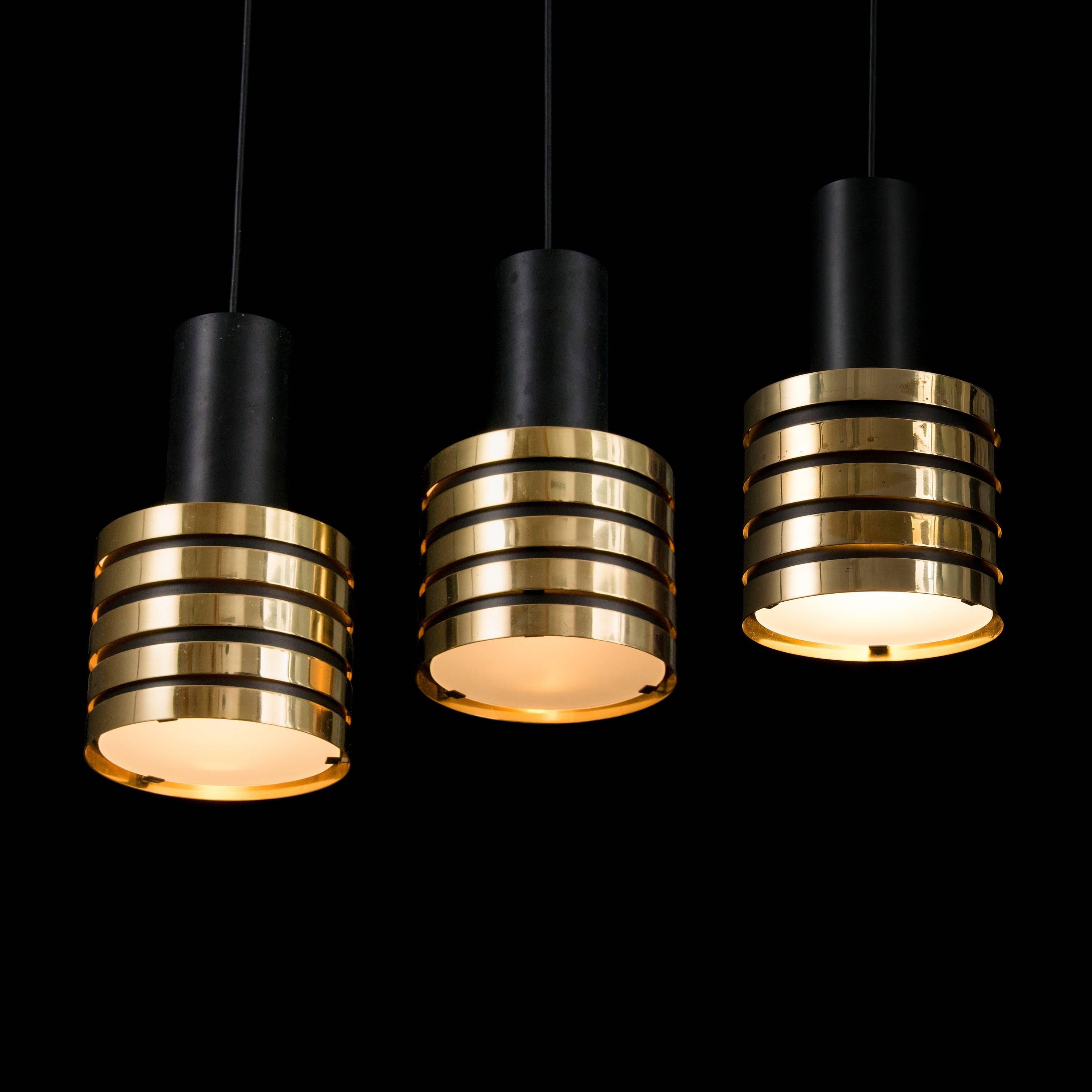 1950s Paavo Tynell K2-49 brass and glass pendants for Taito Oy. Executed in brass, painted metal and opaline glass. Professionally updated wiring for US electrical, each pendant accommodates a single medium base 75 watt incandescent bulb (higher