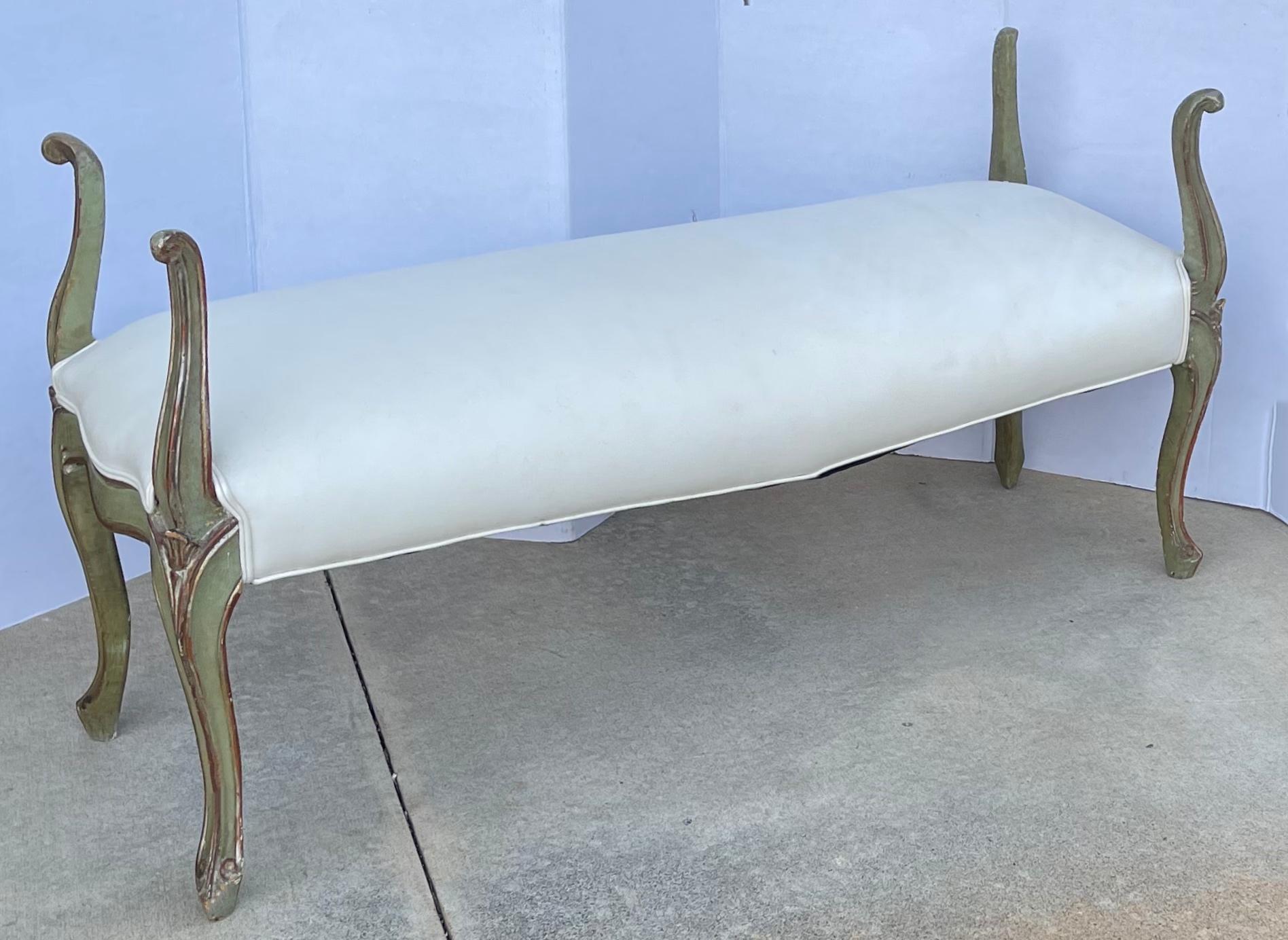 This is a 1950s painted green and silver gilt Venetian bench. It is a wonderful transitional piece that can work from the foot of the bed to a hall or a formal living room. The white cotton upholstery is vintage and does show wear.