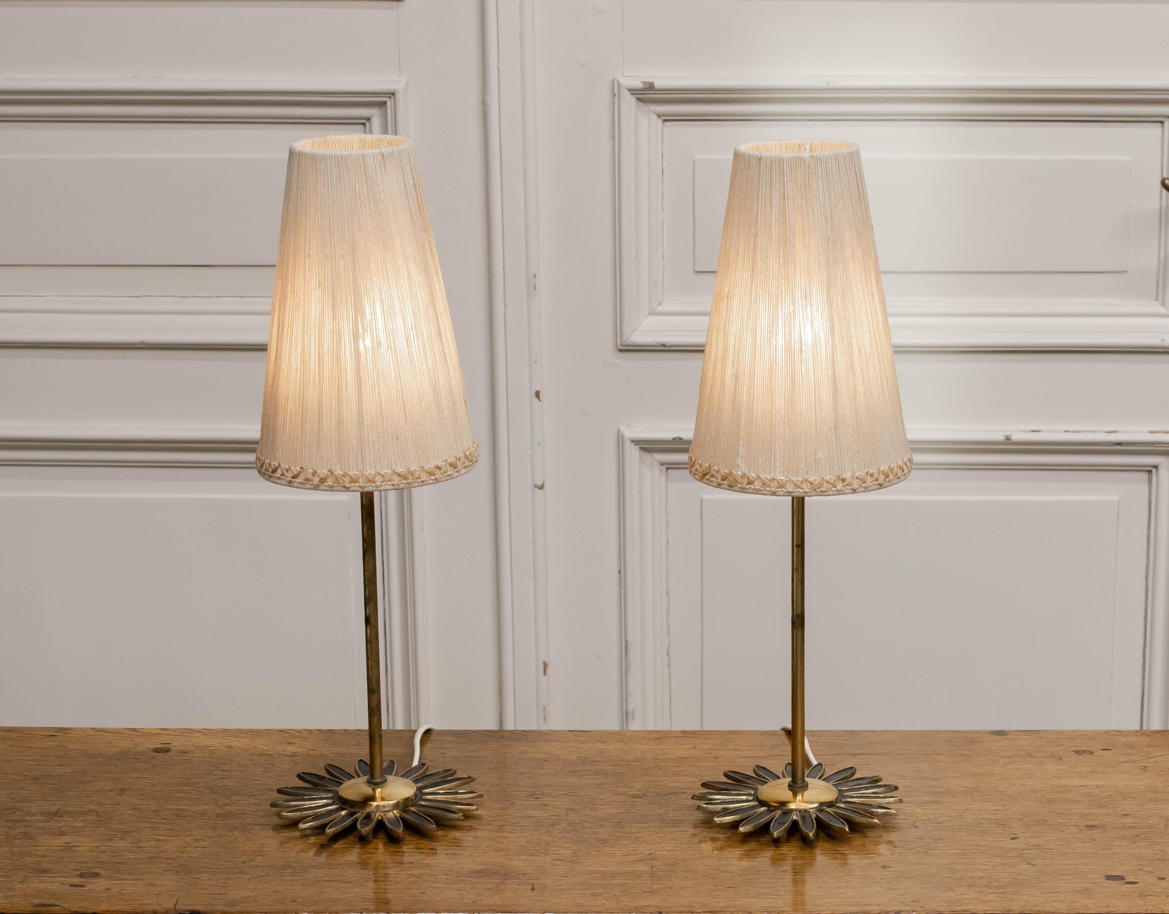 Elegant pair of 1950s Swedish mantel or table lamps, crafted in brass and featuring beautifully detailed “sunburst” bases. Each lamp is topped with an original hand-wrapped linen thread lampshade, creating a warm, softly diffused glow when lit.

The