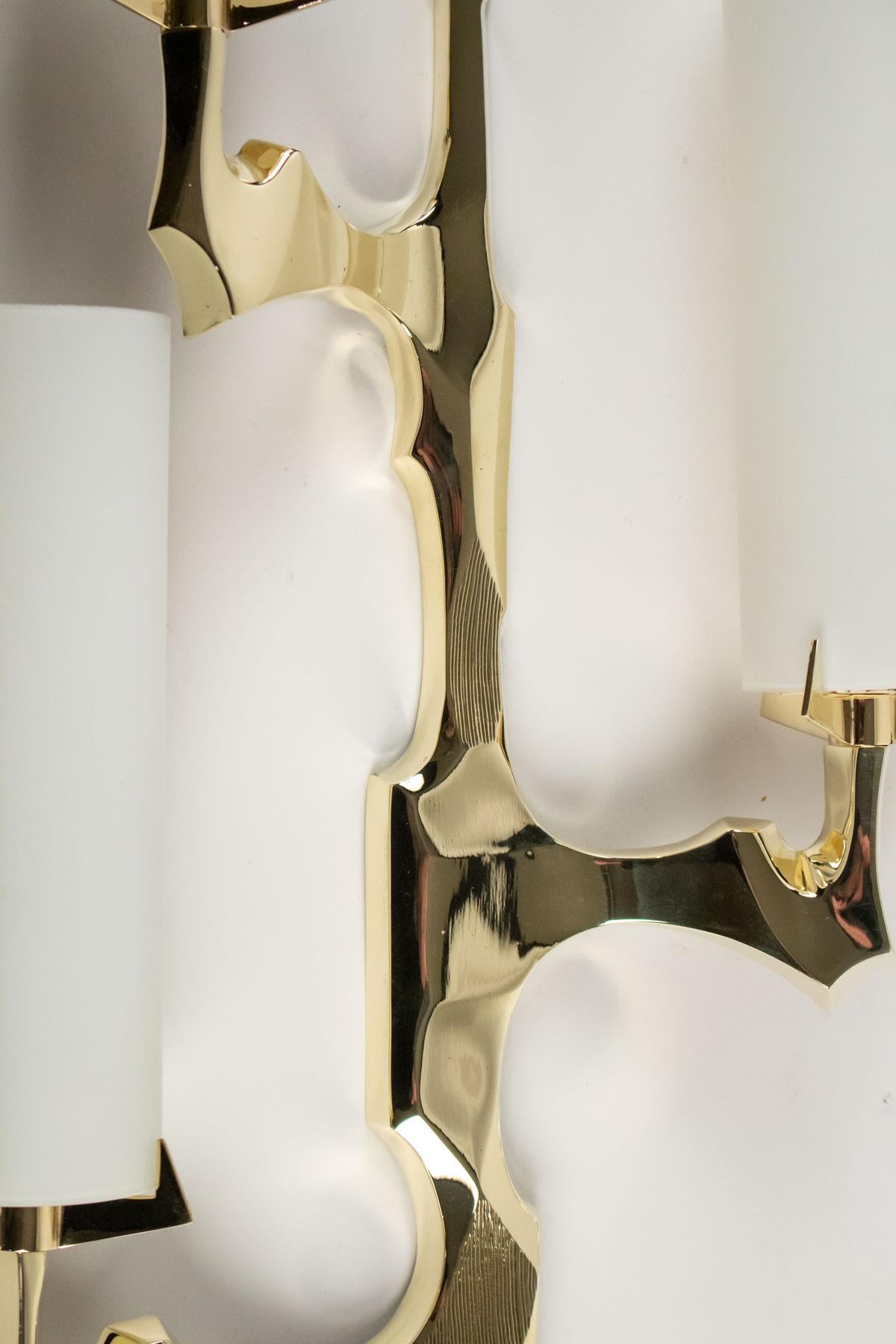 1950s Pair of Arlus Bronze Sconces
The sconces are made of gilded bronze and feature three bulbs with cylindrical opalin glass shades. 
The pair is composed with to symmetrical sconces.
Manufactured by Arlus, 1950s, France.