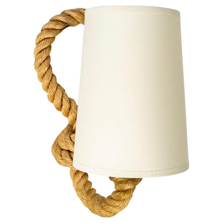 Chaque applique est composée d'un bras de corde se prolongeant sur la partie supérieure pour former une boucle.
Sur la partie inférieure, le bras de lumière revient vers l'avant, il est habillé d'un abat-jour en coton blanc cassé de forme