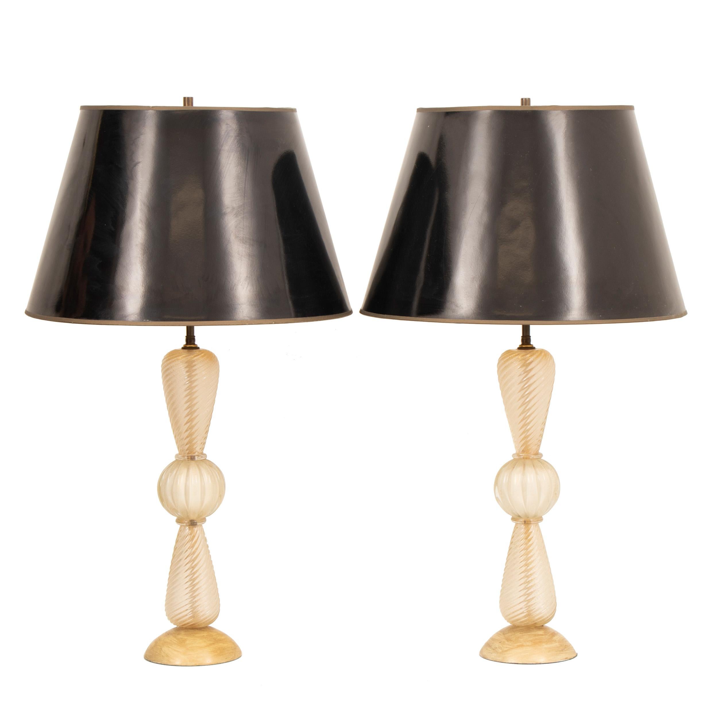 A stunning pair of 1950s Barovier & Toso Italian Murano glass table lamps with an unusual swirl design with gold flecked interiors. The lamps retain their original black gloss shades with gold foil interior. The wooden base has been hand painted