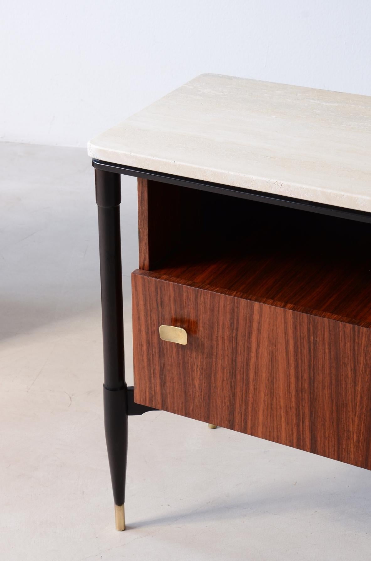 Pair of elegant walnut nightstands with four turned legs, held by a crosspiece supporting a central body closed by a door and an open compartment, and a travertine top.

Italian manufacture, ca. 1955.