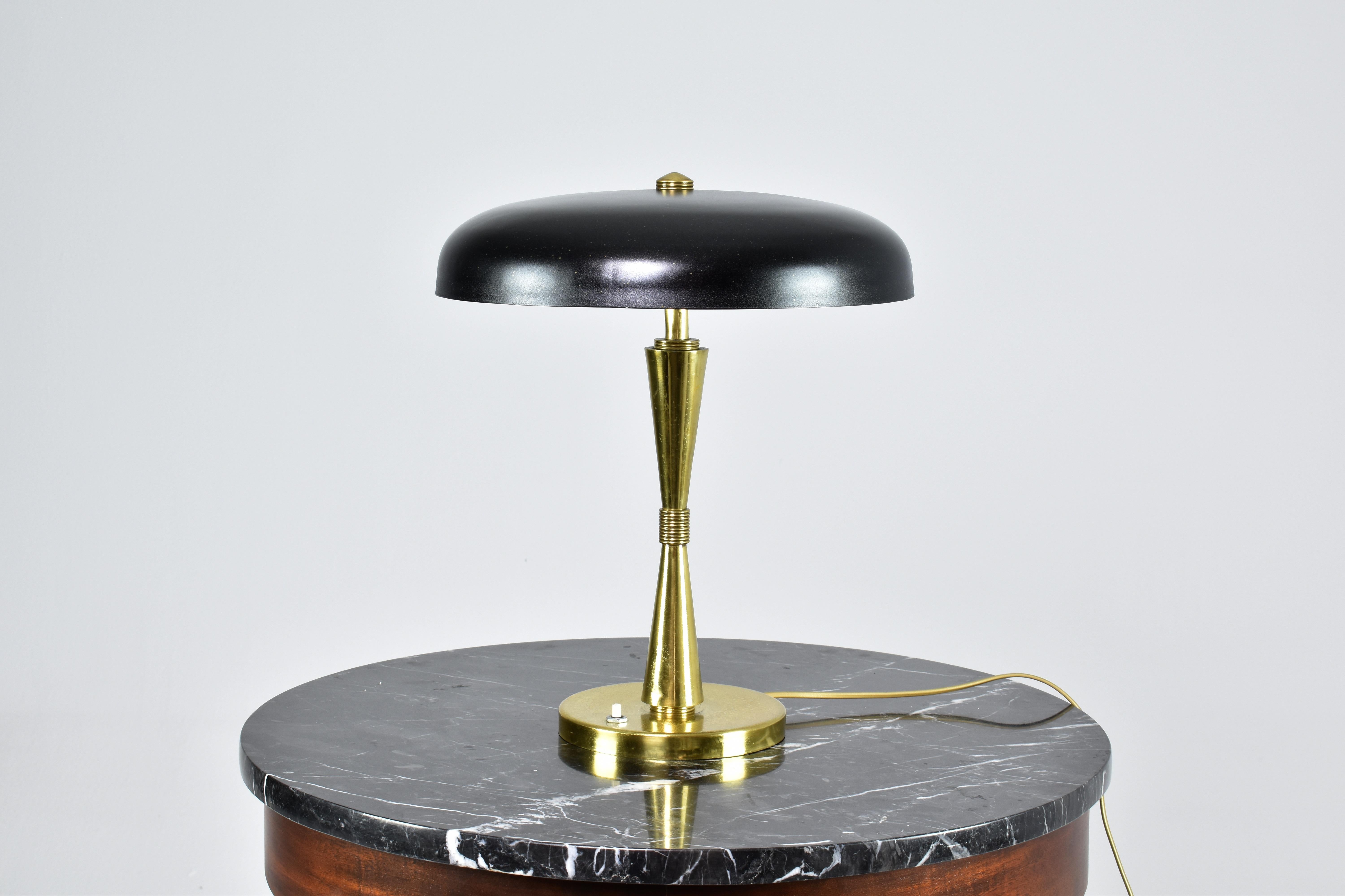 A stylish 1950s Italian mid-century modern table lamp with an elegant brass structure and a black lacquered metal circular shade. 
Push type switch at the base. 
Fits two e14 bulbs. 

New wiring. 
This piece is professionally re-wired with the