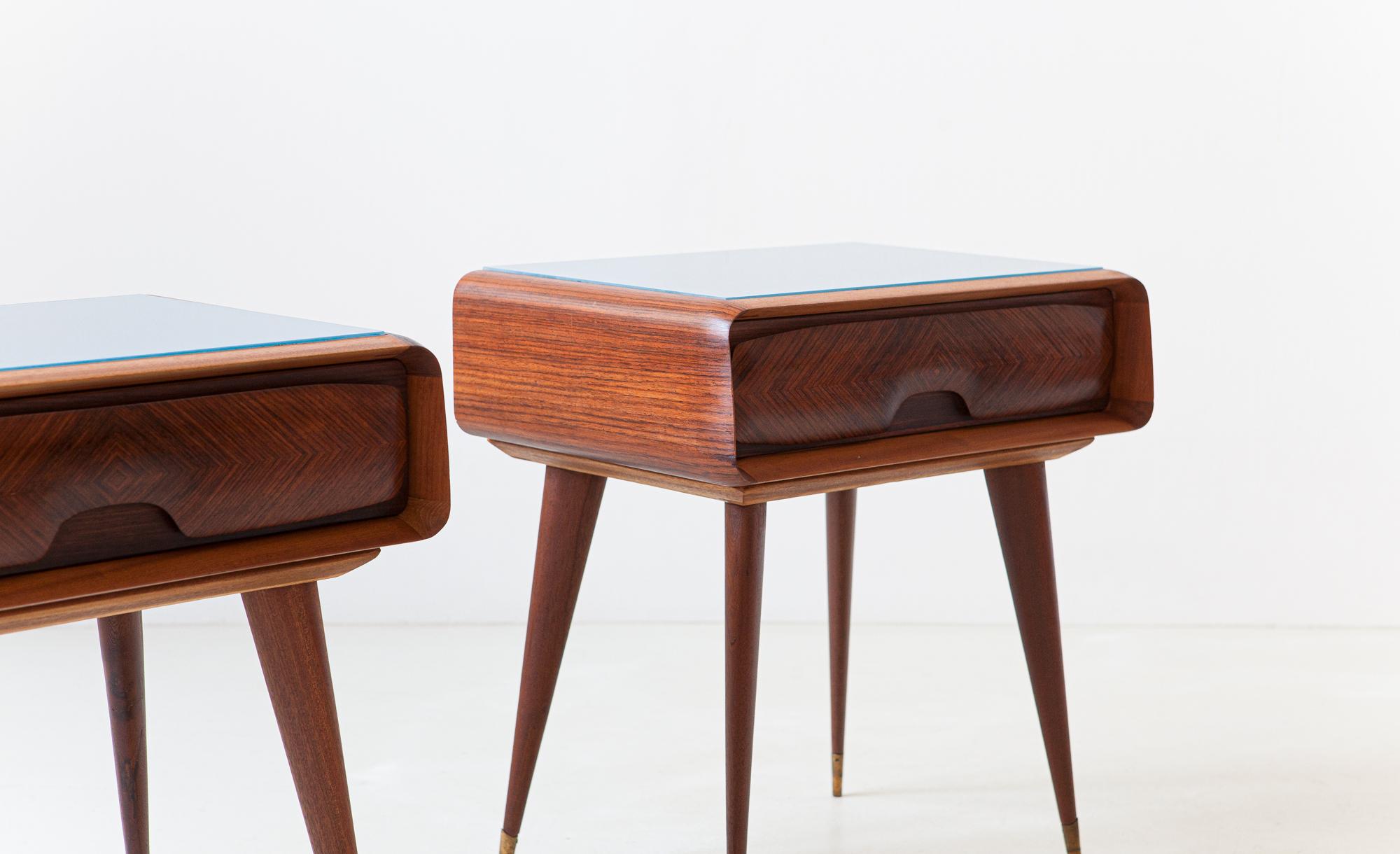 Pair of elegant and modern bedside tables, manufactured in Italy during the 1950s

They are made of mahogany wood with glass retrolaquered top and brass ferrule.

You can see the high-level Italian craftsmanship from all the wood millings,