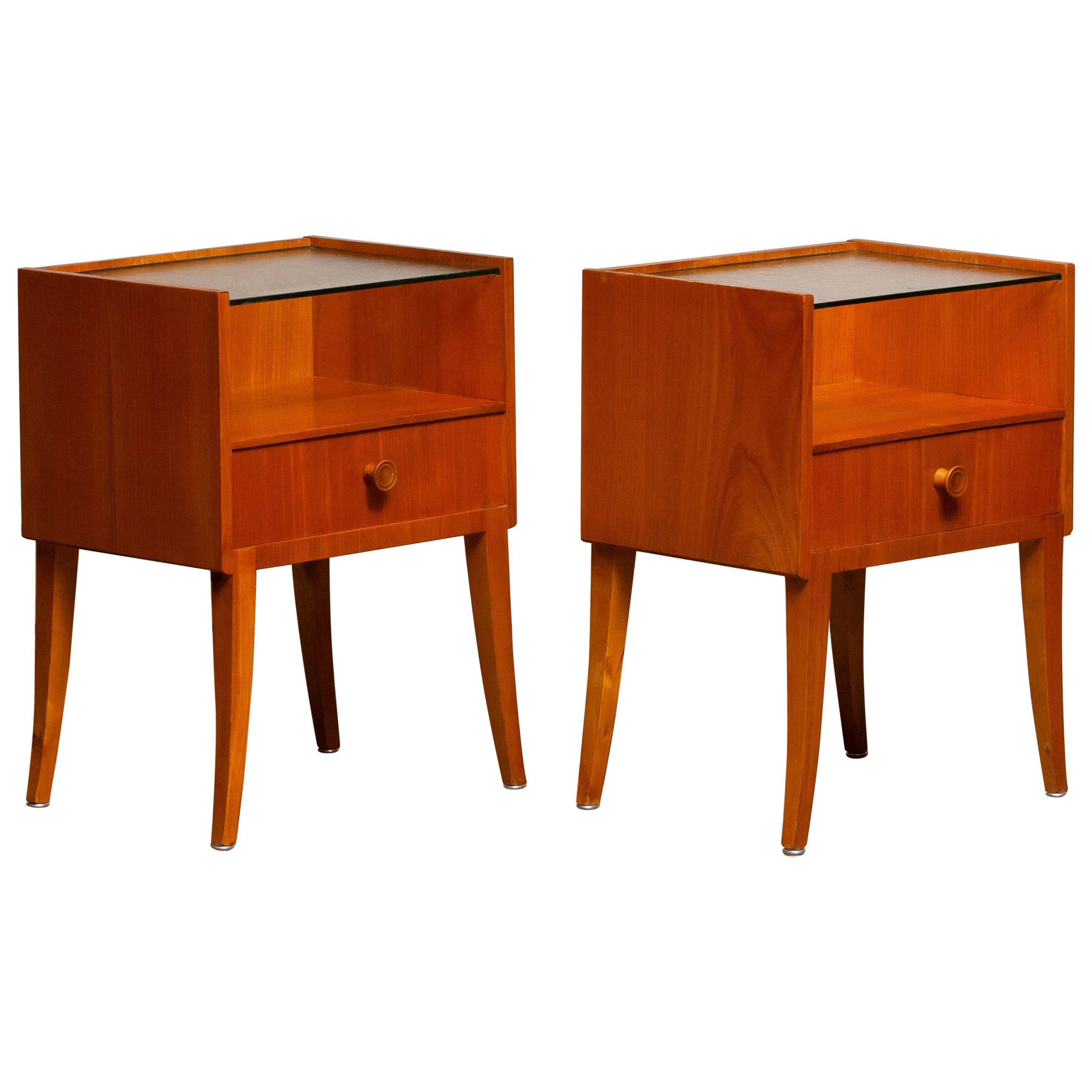 Very elegant set of two Scandinavian nightstands or bedside tables made in elm with a glass toping from Sweden.
The nightstands or bedside tables are overall in good condition.