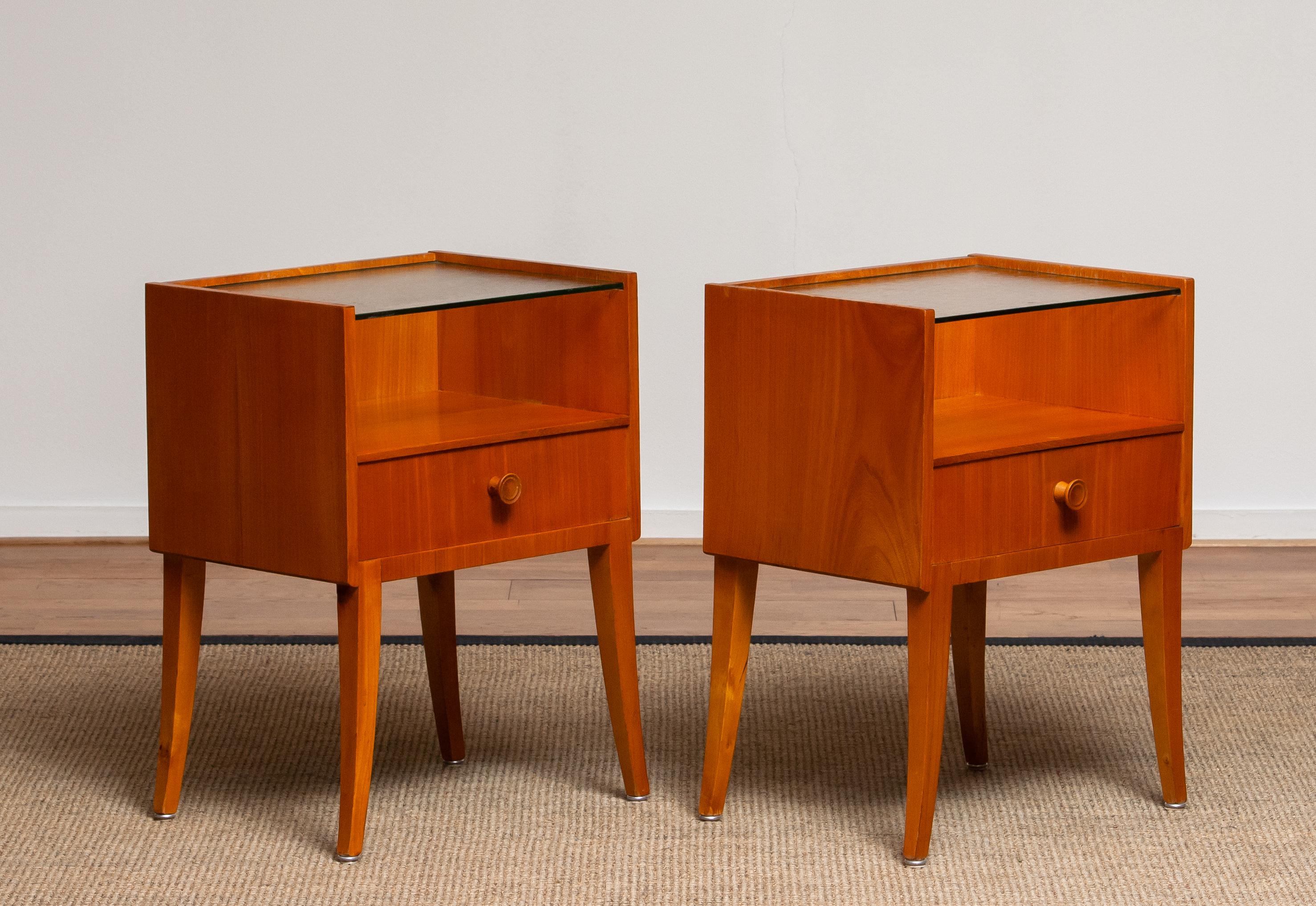Very elegant set of two Scandinavian nightstands or bedside tables made in elm with a glass toping from Sweden.
The nightstands or bedside tables are overall in good condition.