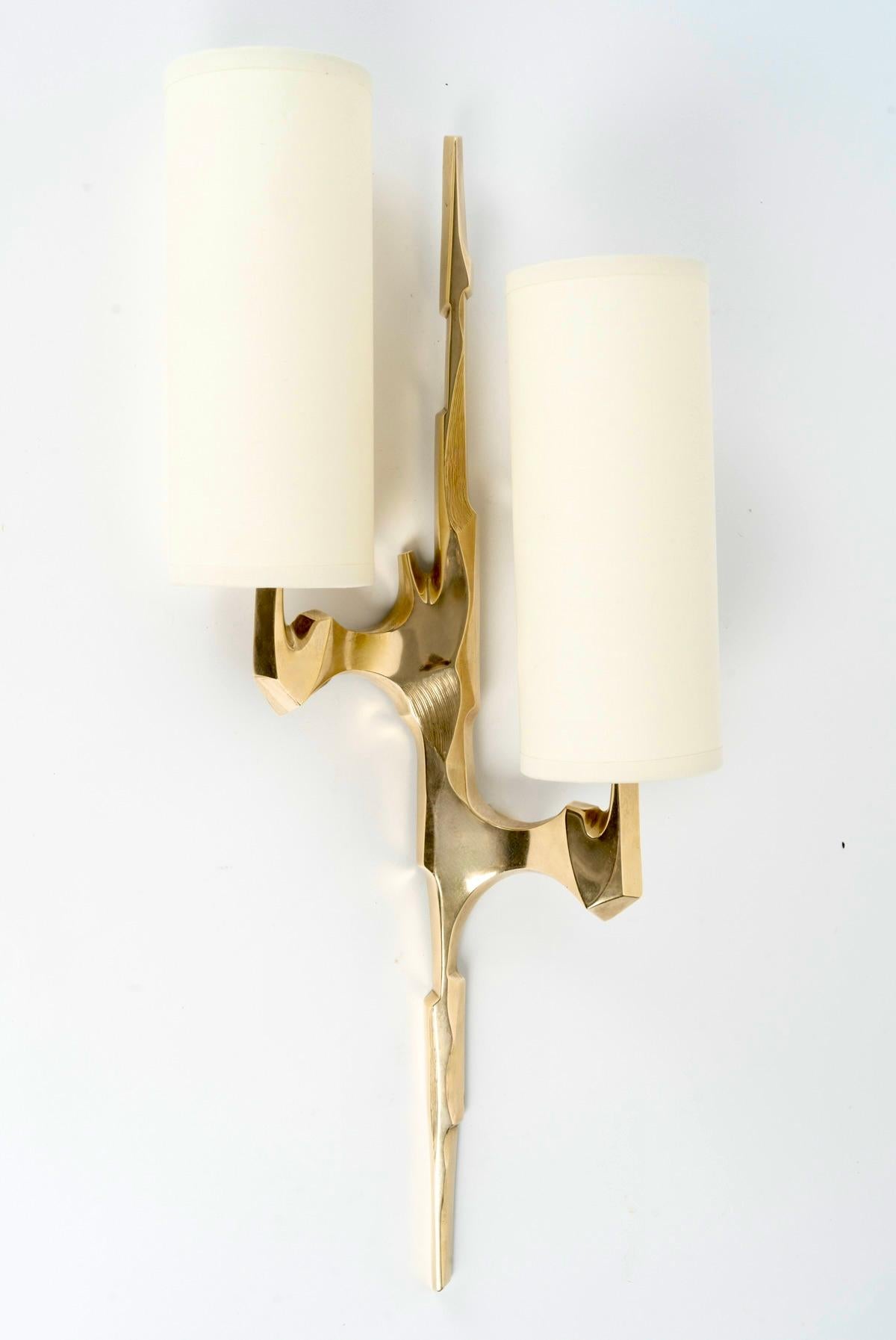 La coppia di applique in bronzo dorato si ispira ai rami degli alberi. Ogni applique è composta da un braccio centrale sul quale sono posizionati due bracci ai lati dell'applique, a due altezze diverse. Entrambi i bracci sono ricoperti da paralumi