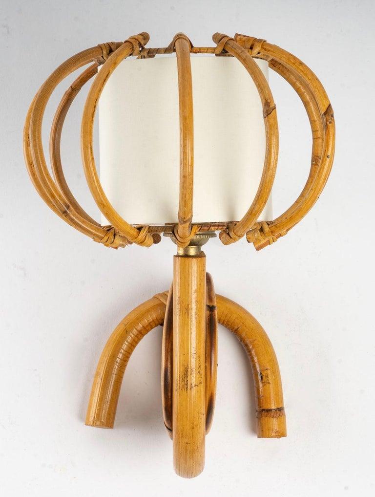 Composed of a wall support in a descending semicircle on which is fixed an ascending arm of light on which is placed a cylindrical shade in openwork rattan, the interior is dressed in an ecru cotton shade.
It is decorated with a double rattan circle