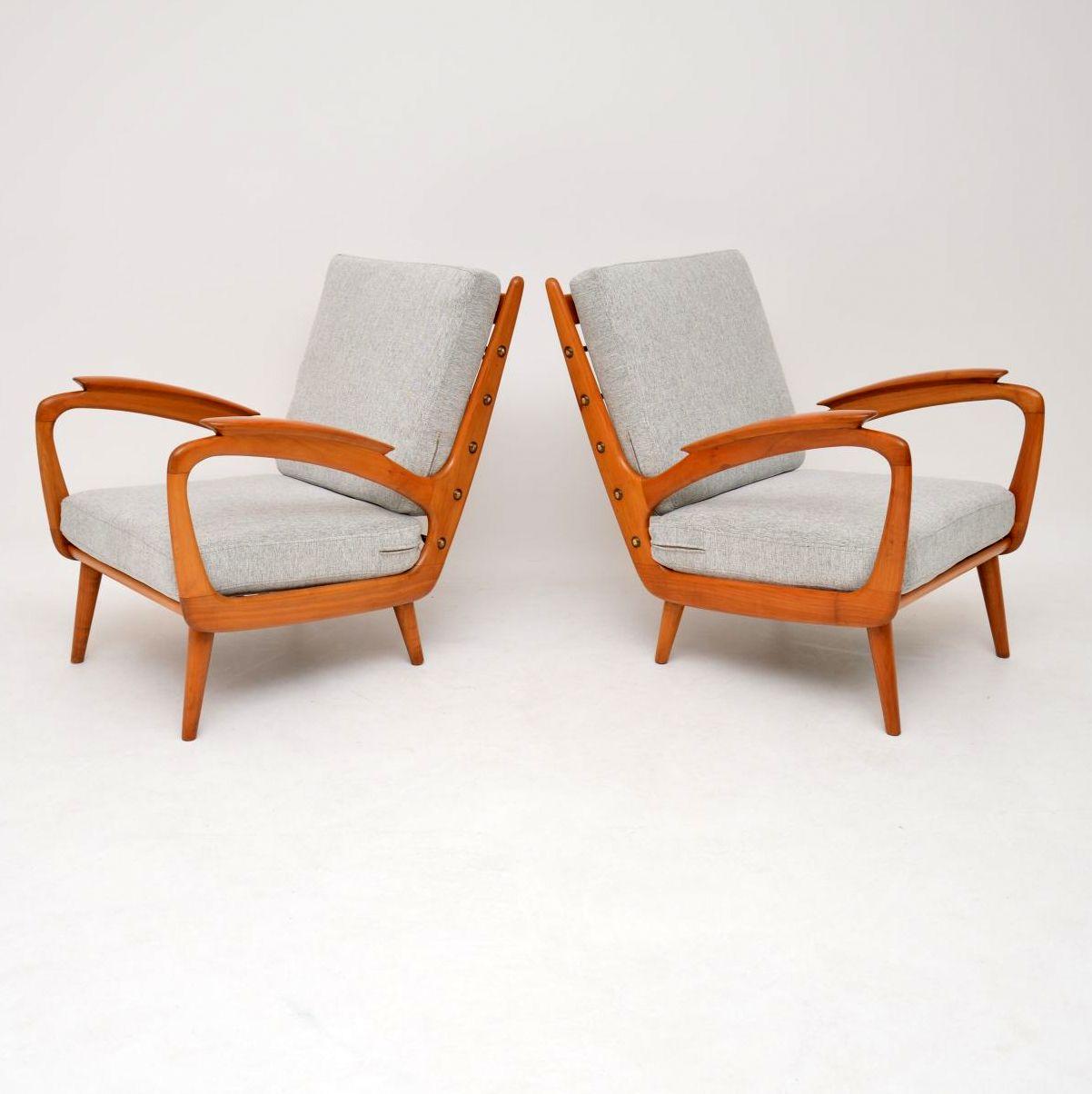 A stylish and extremely comfortable pair of vintage armchairs in solid cherrywood, these date from the 1950s-1960s. We have had the frames stripped and re-polished to a very high standard, they are in superb condition. The original sprung cushions