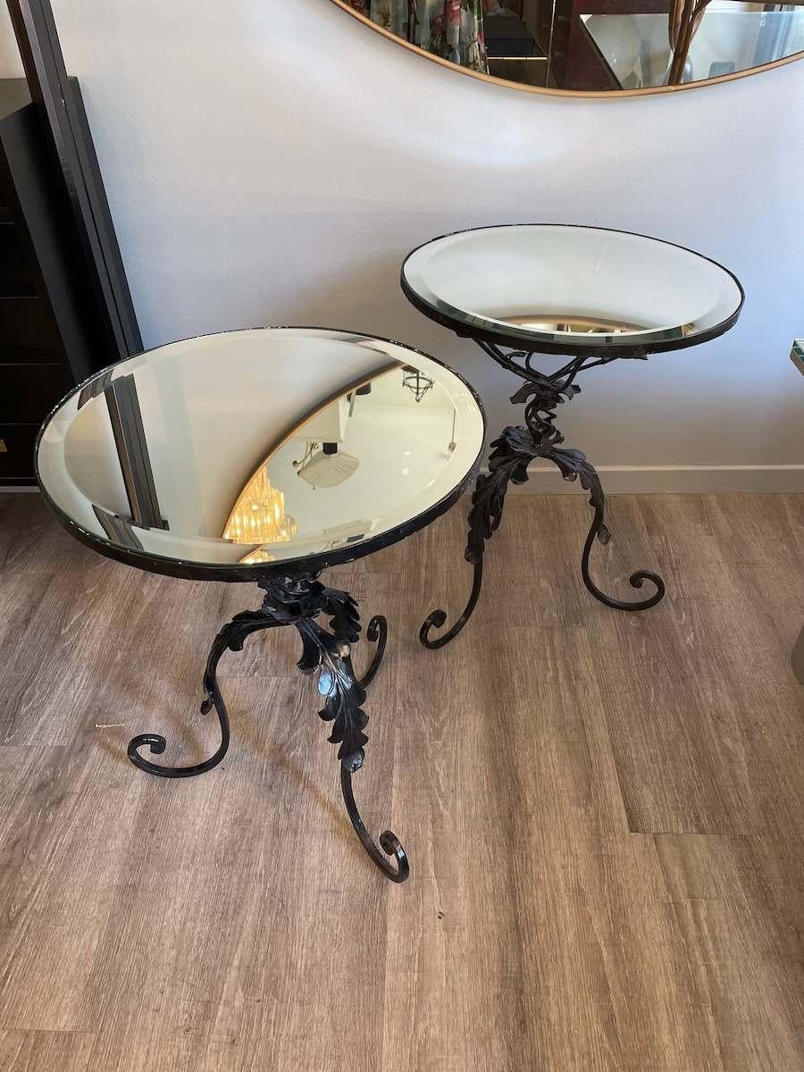 Paire de tables basses en fer forgé des années 1950 avec plateau en miroir biseauté. Les pieds de la table sont en forme de tige avec des fleurs. Le plateau de la table est constitué d'un miroir entouré de meulage. Les tables basses présentent de