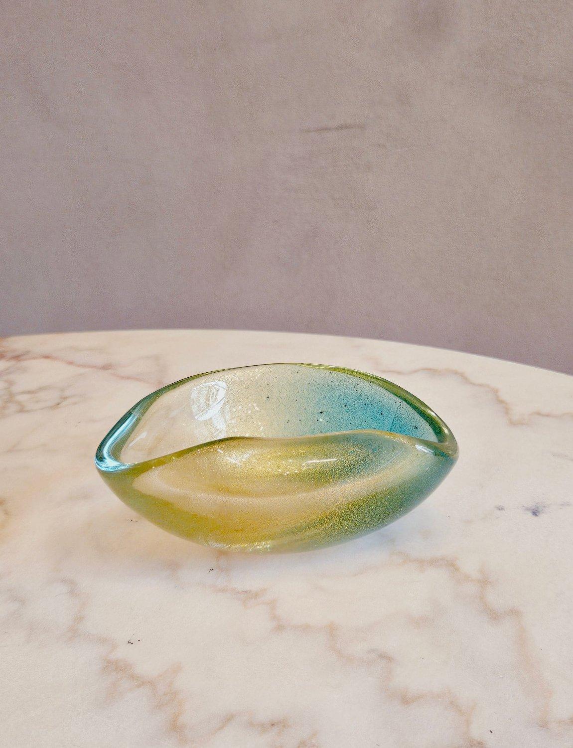 Infused throughout with gold flecks, this hand-blown organic Murano glass bowl was made in the 1960s. It is predominantly pale green with a flush of turquoise. A lovely piece for a coffee or dressing table.