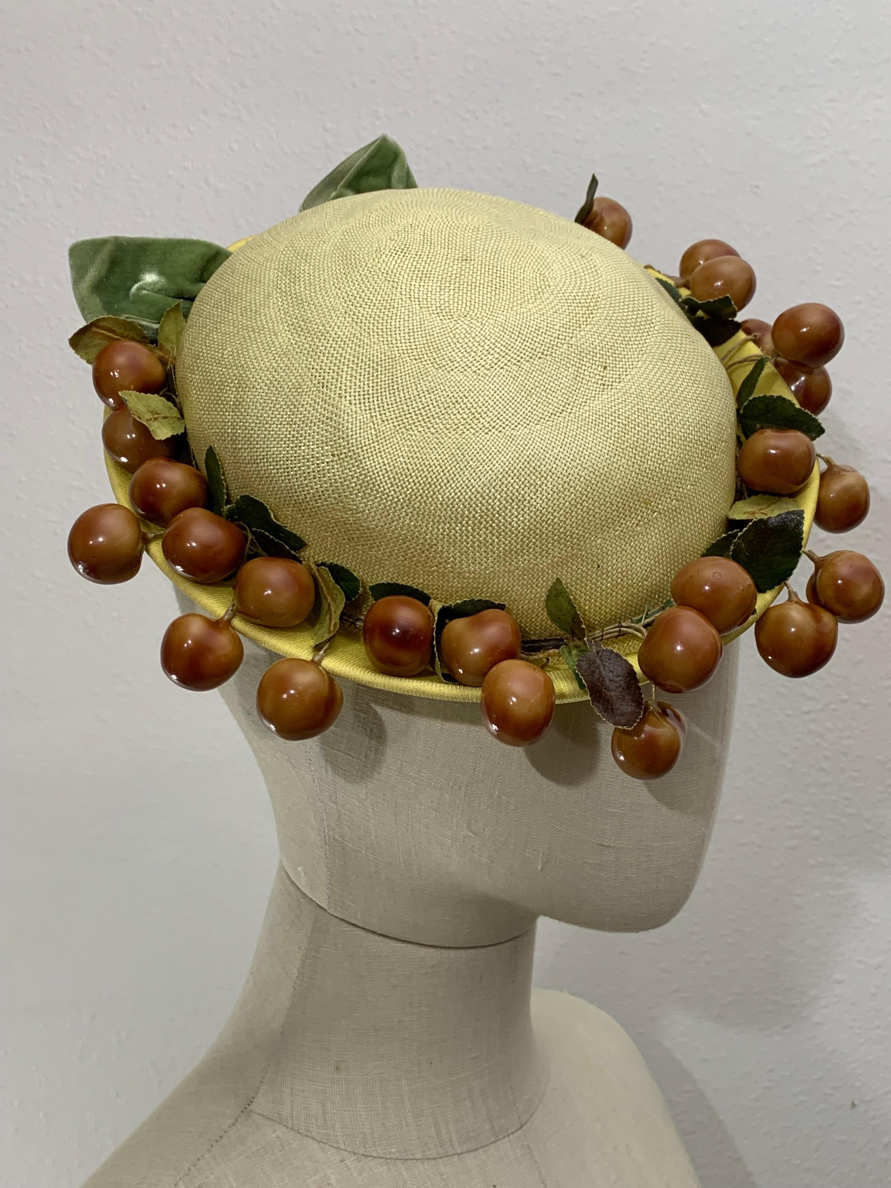 1950s Pale Yellow Straw Boater Hat w/ Olive Green Bow & Glossy Cherries At Brim: A delightfully whimsical summer hat with a short rolled brim in a butter yellow color with reddish-brown faux cherries surrounding.  A real charmer. Limited edition or