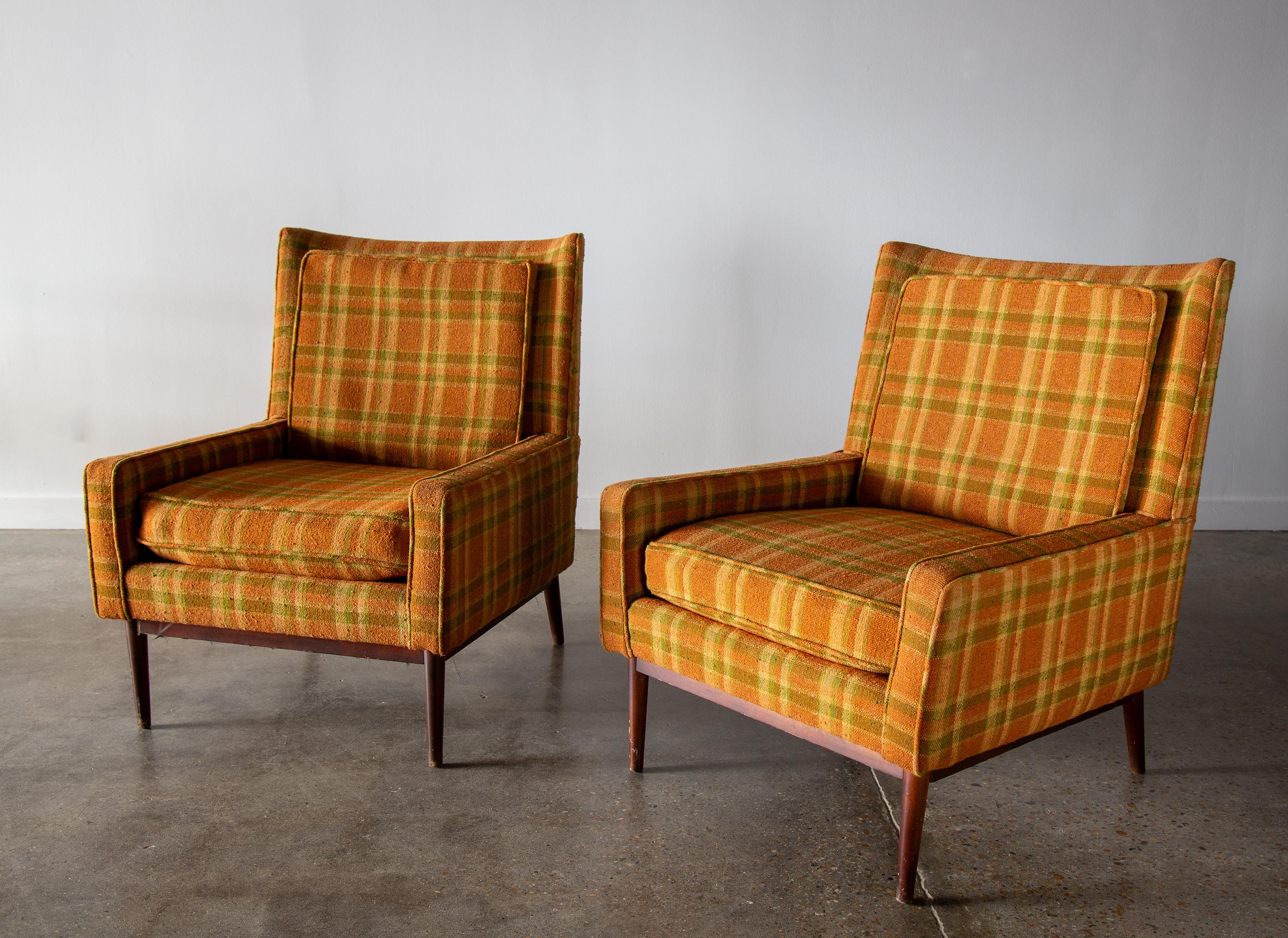A pair of 1950s Model 312 armchairs designed by Paul McCobb for Directional. Original orange based plaid featuring green and yellow accent stripes. Solid walnut legs and stretches. Subtle curved back accented with a thin almost full height pillow.