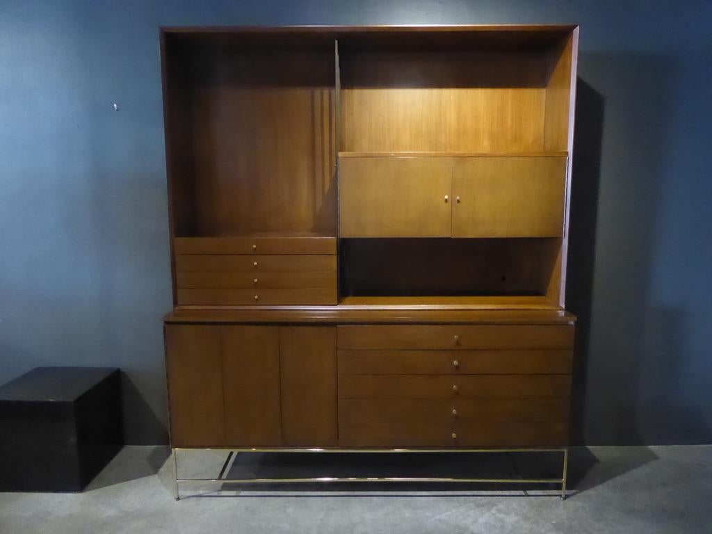A mahogany and brass credenza / wall unit designed by Paul McCobb for his Irwin collection produced by Calvin Furniture, circa 1950s. The wall unit has a combination of drawers and cabinets with the top section resting on the lower. The original