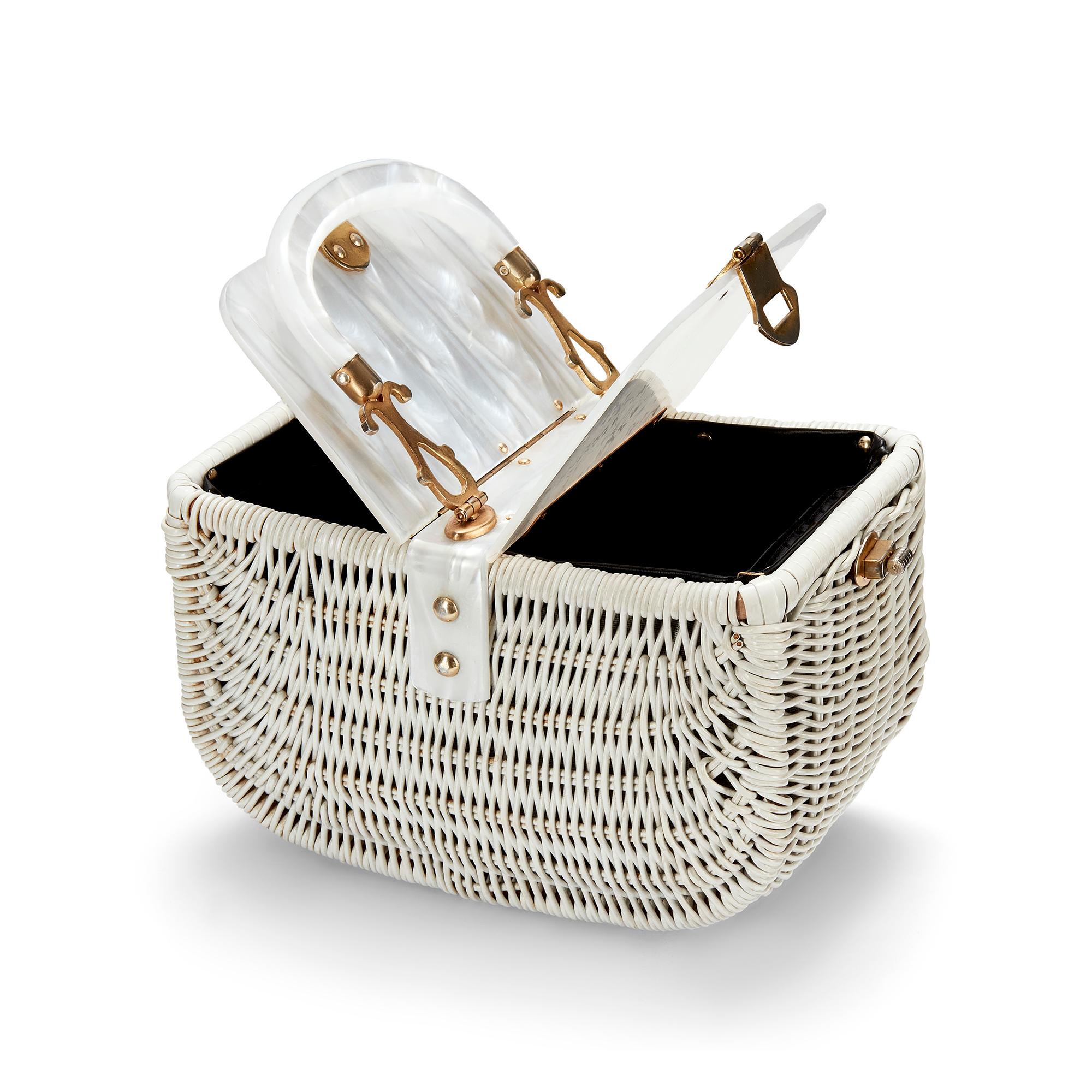 This super-sweet basket bag was created in the 1950s. It has a white woven lacquered body and is finished with a decadent pearlescent lucite top. The lid opens on two sides and is secured with intricate gold-toned brass hardware. The elaborate