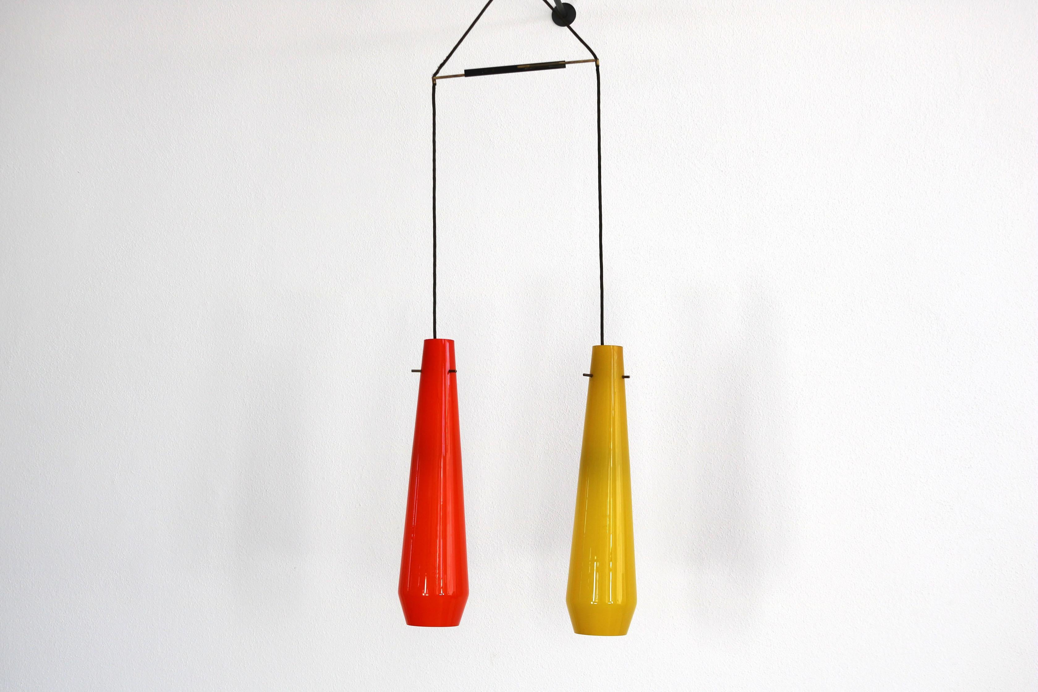 Pendant lamp from the Italian 1950s with two mouth-blown glass shades in yellow and orange. Total height currently 136 cm. One glass shade is 40 cm high and has a diameter of 16 cm. The distance holder is made of iron and patinated brass.