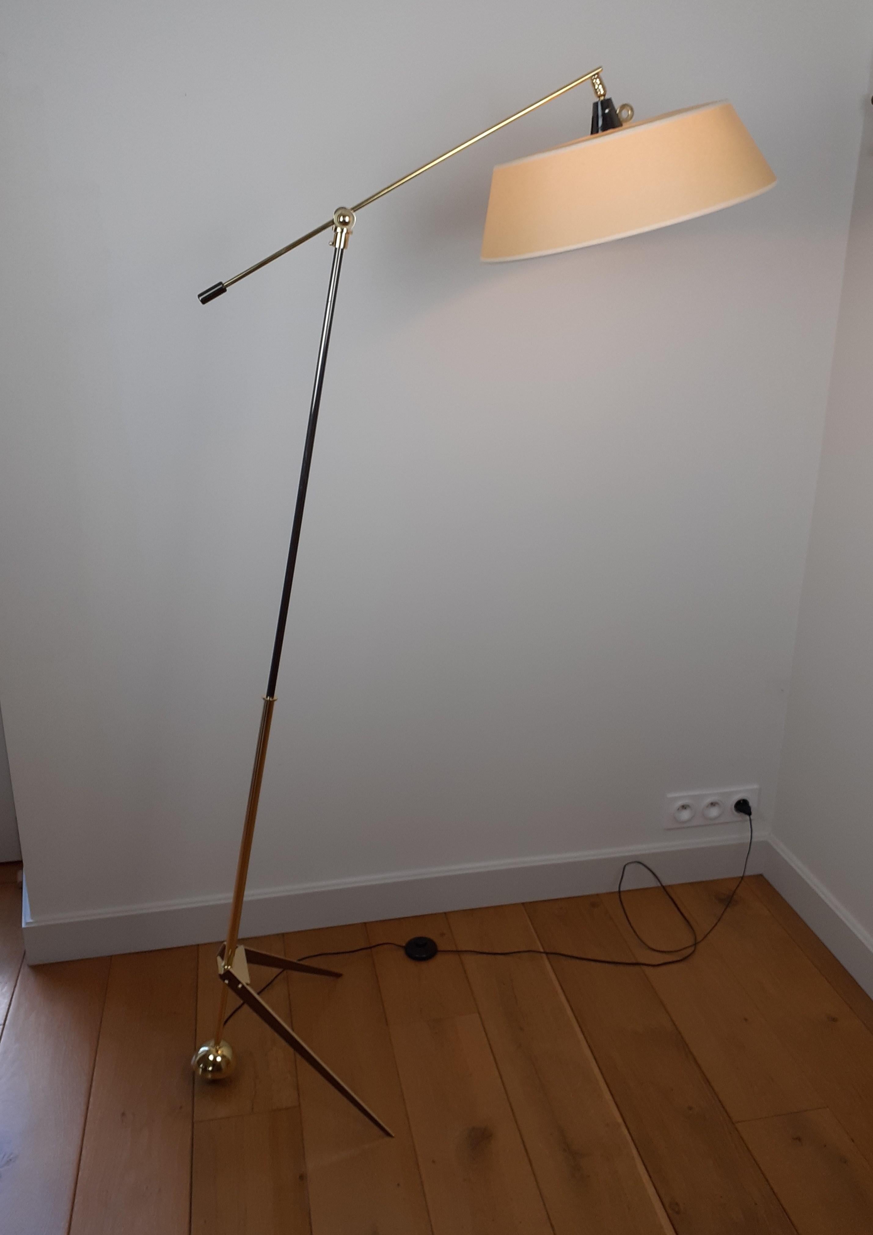 Floor lamp with pendulum and ball joint in brass with gunmetal patina, composed of a compass foot in brass and gunmetal patina. A ball joint is used to tilt the arm of light.
A round and slightly conical lampshade oriented by a brass ball joint is