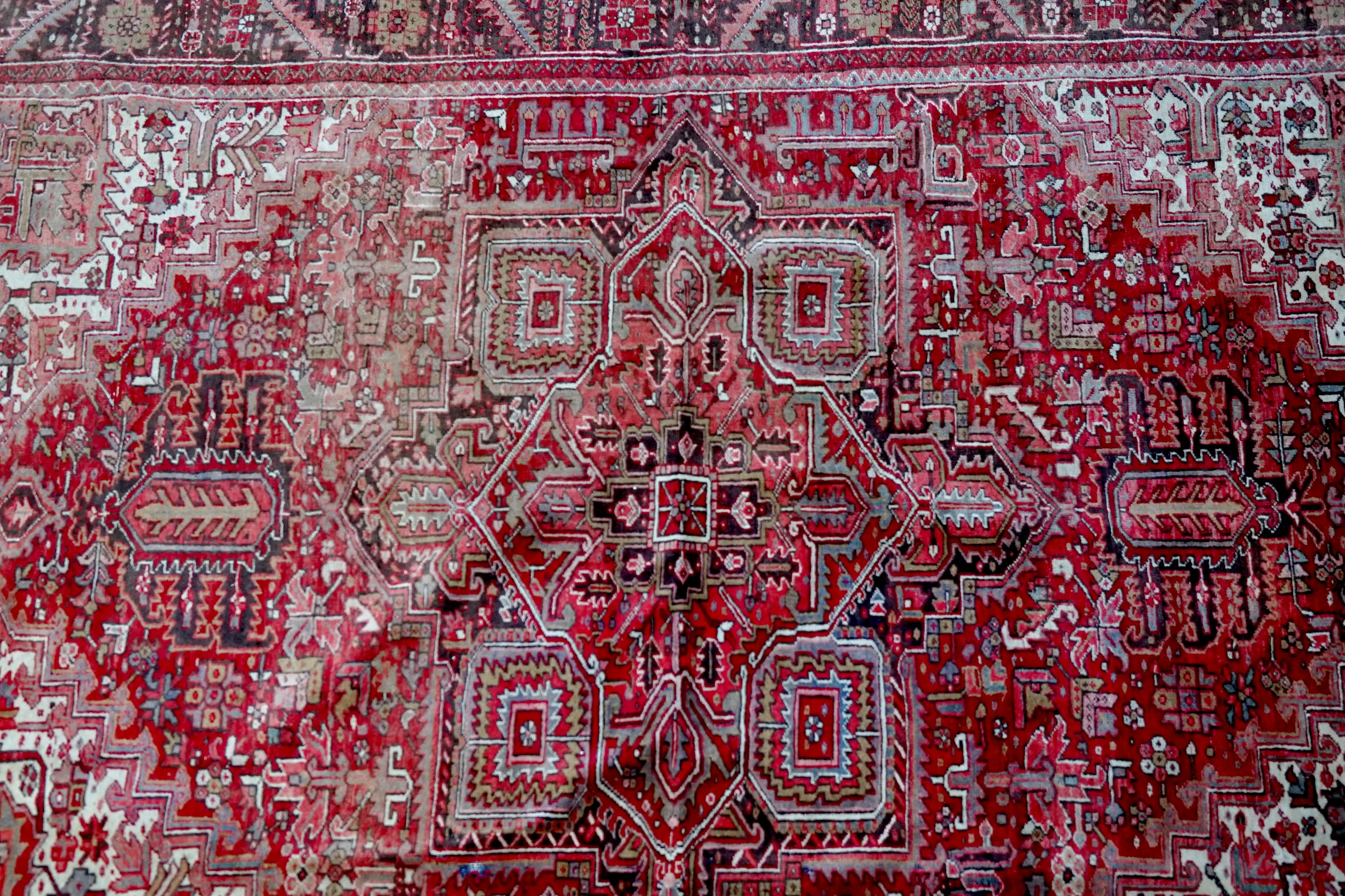 Rich reds, ivory and royal blues form the palette of colors for this 1950s Heriz Persian carpet to treasure. The red field features a large central pointed rectangular medallion linked to mirrored stepped pendants. Blue and ivory are normally added
