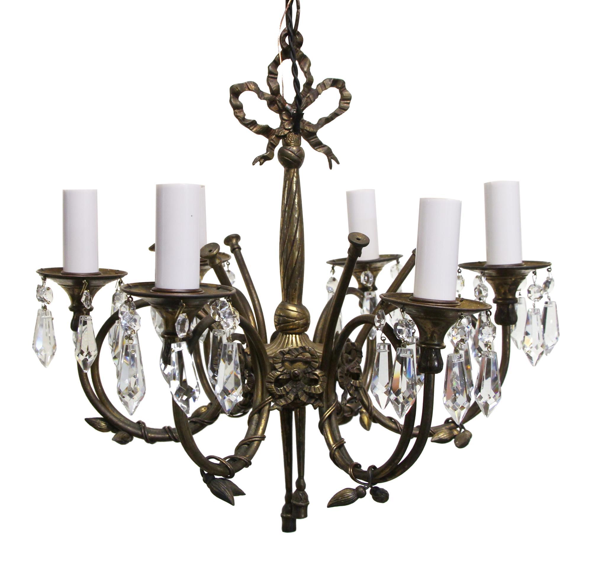 1950s delicate and petite Spanish bronze six candlestick arm chandelier with pretty leaf and ribbon details and beautiful crystals. This can be seen at our 2420 Broadway location on the upper west side in Manhattan.
