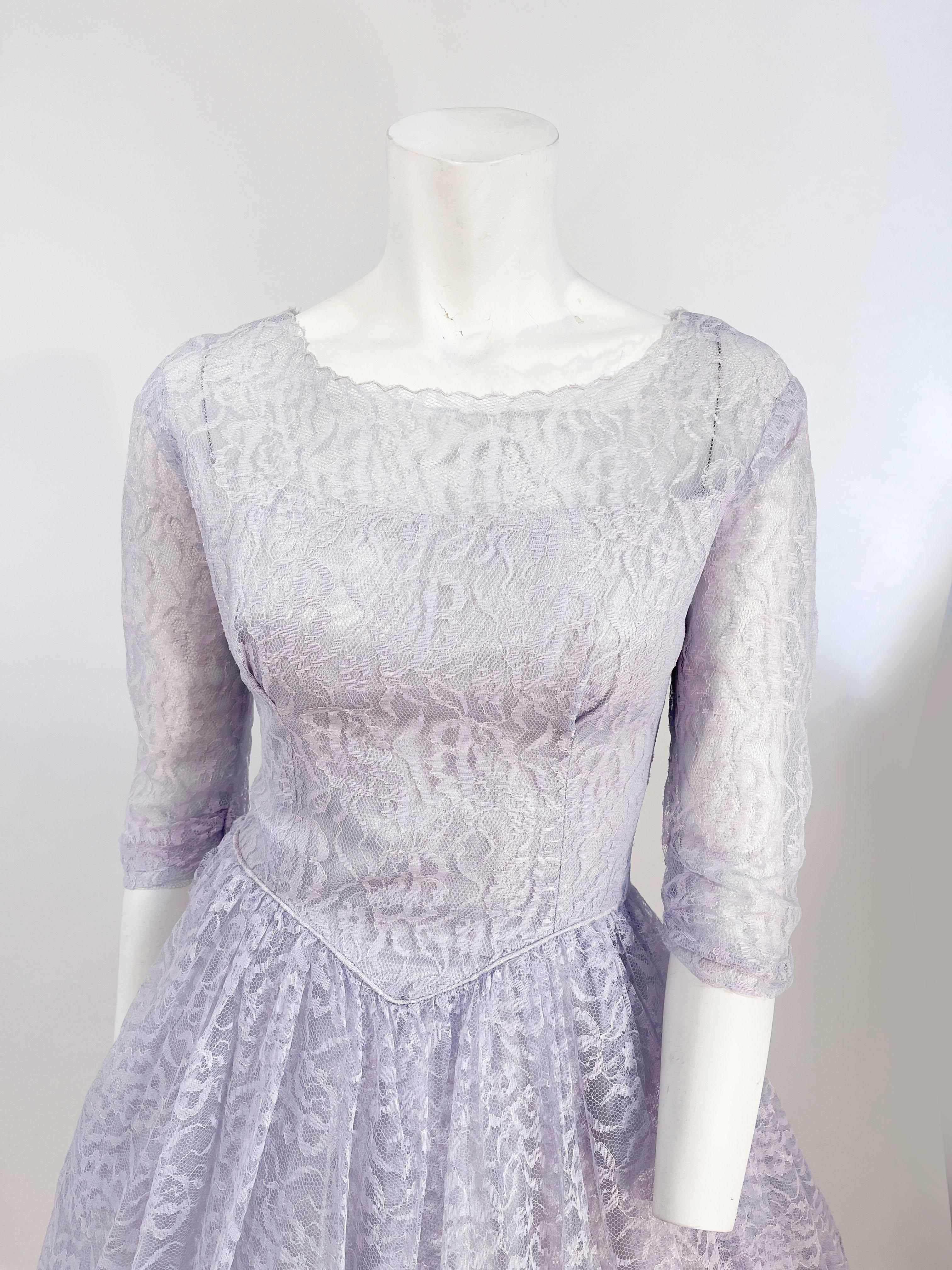 1950er Jahre Zinn/Lavendel geblümte Spitze Partykleid. Das taillierte Mieder hat einen transparenten Bootsausschnitt, der zu den gerafften Ärmeln in Dreiviertellänge passt, und eine geraffte Taille, die in einen t-förmigen Rock aus Spitze und Tüll