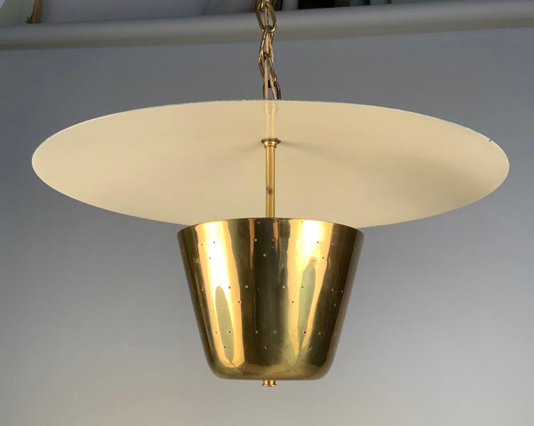 a beautiful 1950's hanging chandelier light fixture by Lightolier. the design has a circular domed shade, lacquered white underneath and forest green above. Underneath the shade is a polished brass bowl which has a series of small pierced holes.