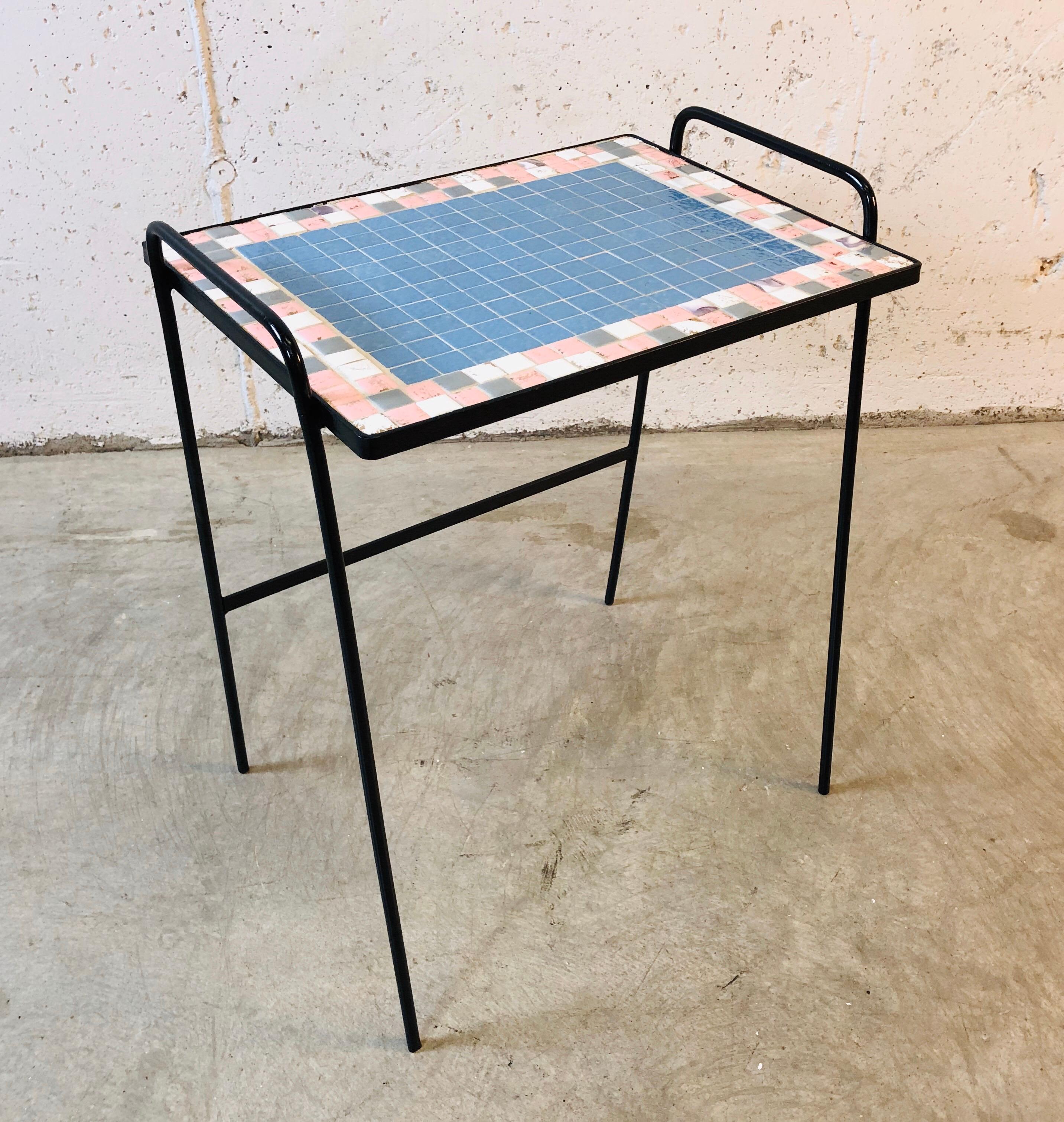 Vintage 1950s pink, blue, gray and gold accented tile top side table on a black metal base. The table has been restored and refinished and is in excellent condition. With the handles, 21”H. No marks.
