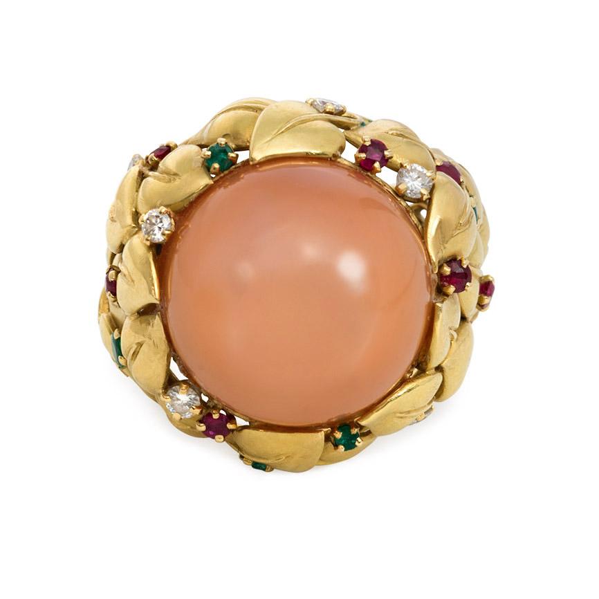 A mid-century gold and pink moonstone cocktail ring in a mount of overlapping leaves set with rubies, emeralds and diamonds, in 18k. 

Dimensions: width 26mm, height 16mm, moonstone 18mm
Current size: US 9 3/4 (Please contact us with re-sizing