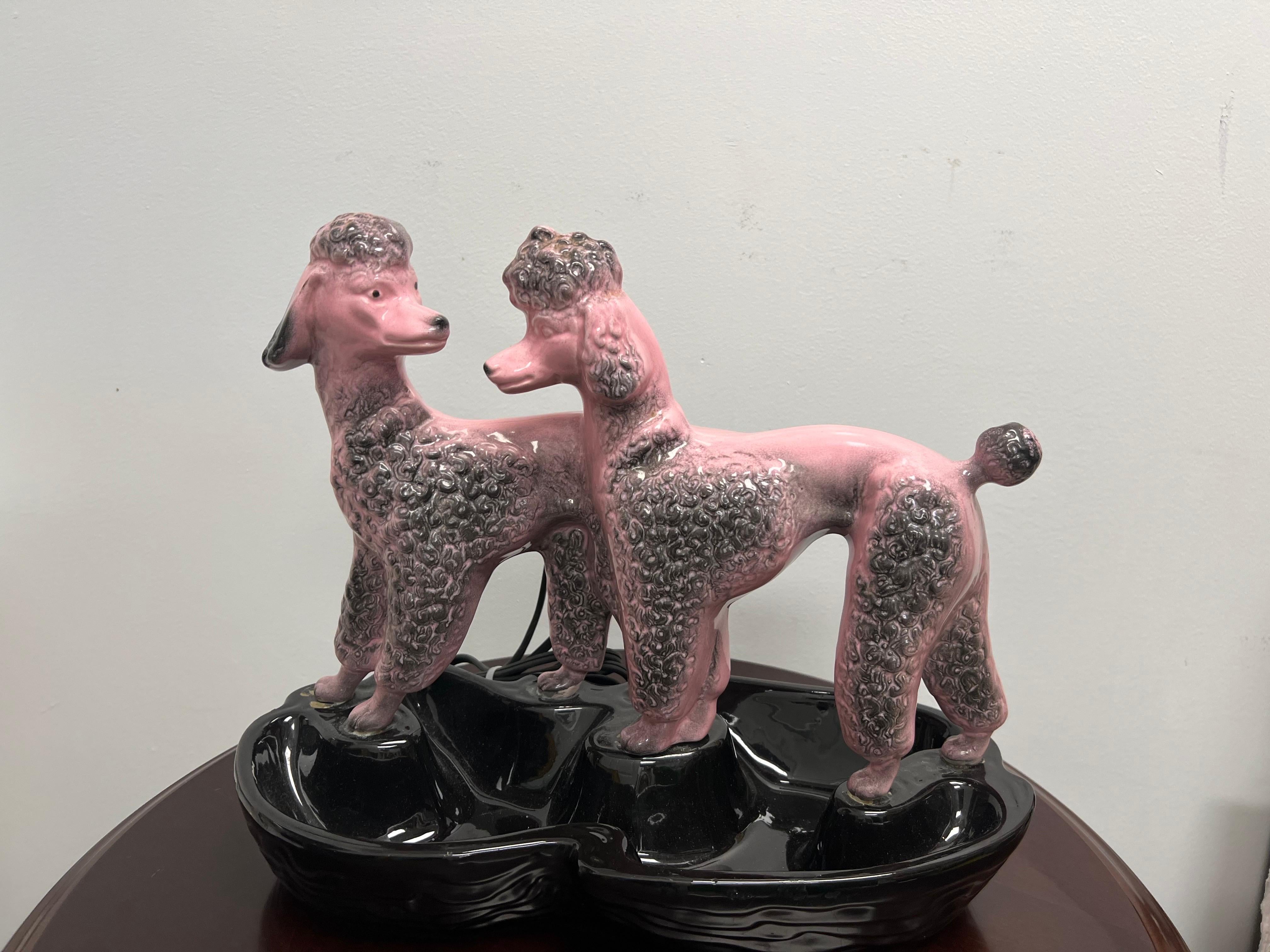 Lampe TV/plante en céramique caniche rose de Lane and Co. d'une grande originalité. Il suffit de jeter un coup d'œil à ce duo canin huppé pour se poser des questions. Un merveilleux exemple de décoration céramique libre d'esprit qui, à n'en pas