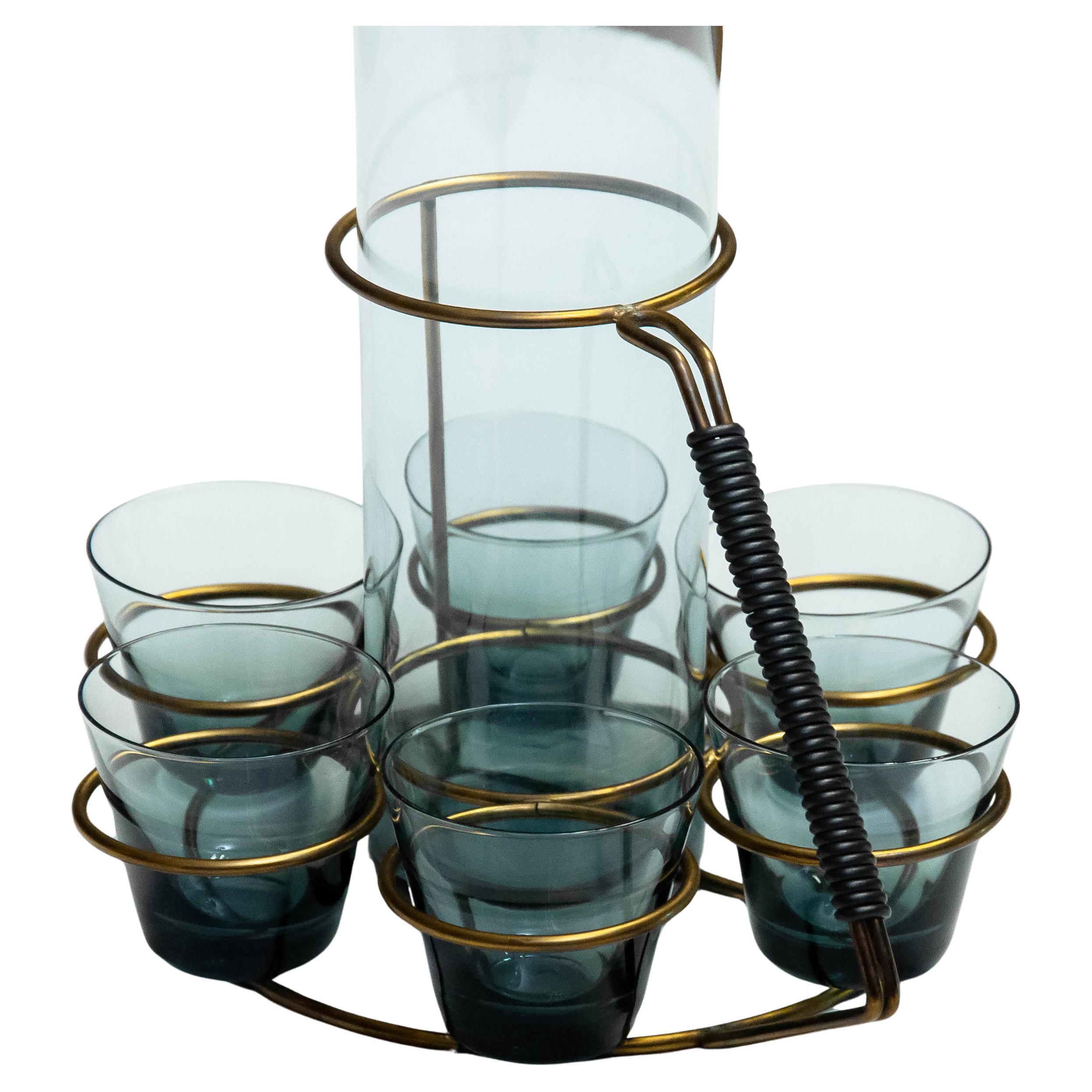 Questo elegante set di caraffe della metà del secolo scorso è stato progettato dall'acclamato designer finlandese Kaj Franck, figura centrale del design scandinavo. Il set comprende una caraffa cilindrica alta in vetro e sei bicchieri coordinati,