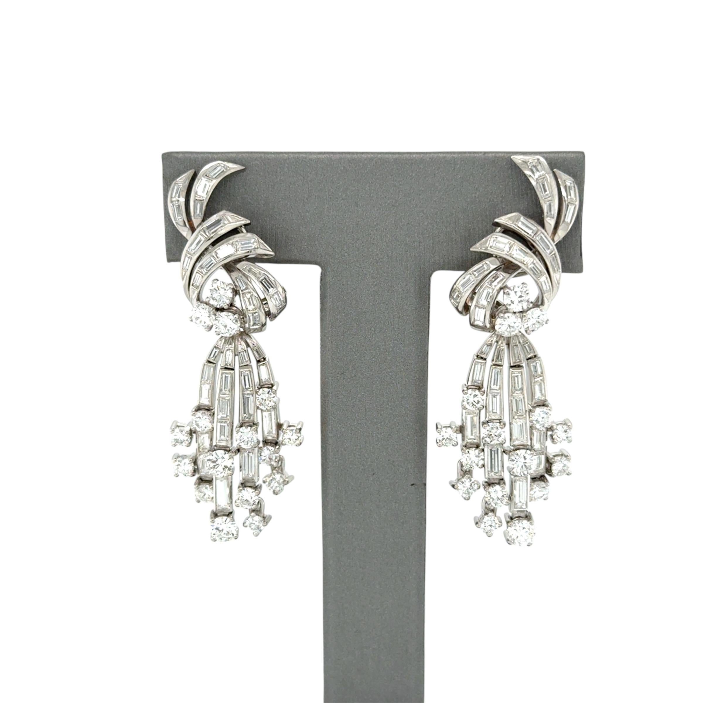 These beautifully crafted earrings contain 32 round brilliant cut diamonds and 70 baguette cut diamonds weighing approximately 9.00 carats total, in a looping tie design with drop. Mounted in platinum and posts with omega clip backs, these are sure