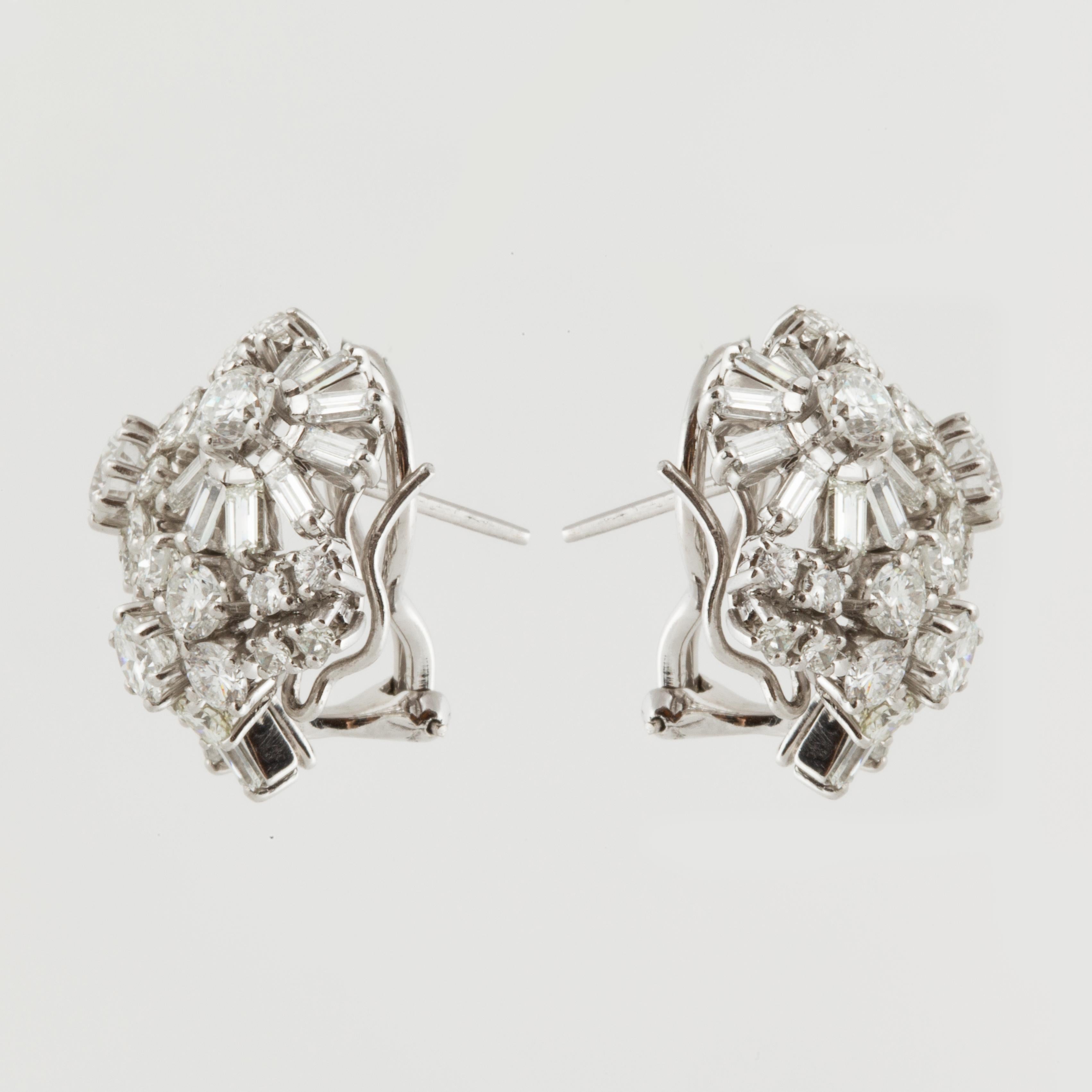 1950s platinum diamond cluster earrings featuring an open frame floral inspired motif studded with 28 baguette-cut and 52 round brilliant-cut diamonds.  The diamonds total 5.15 carats, G-I color and VS1-I2 clarity.  Measure 7/8 inches long and 3/4