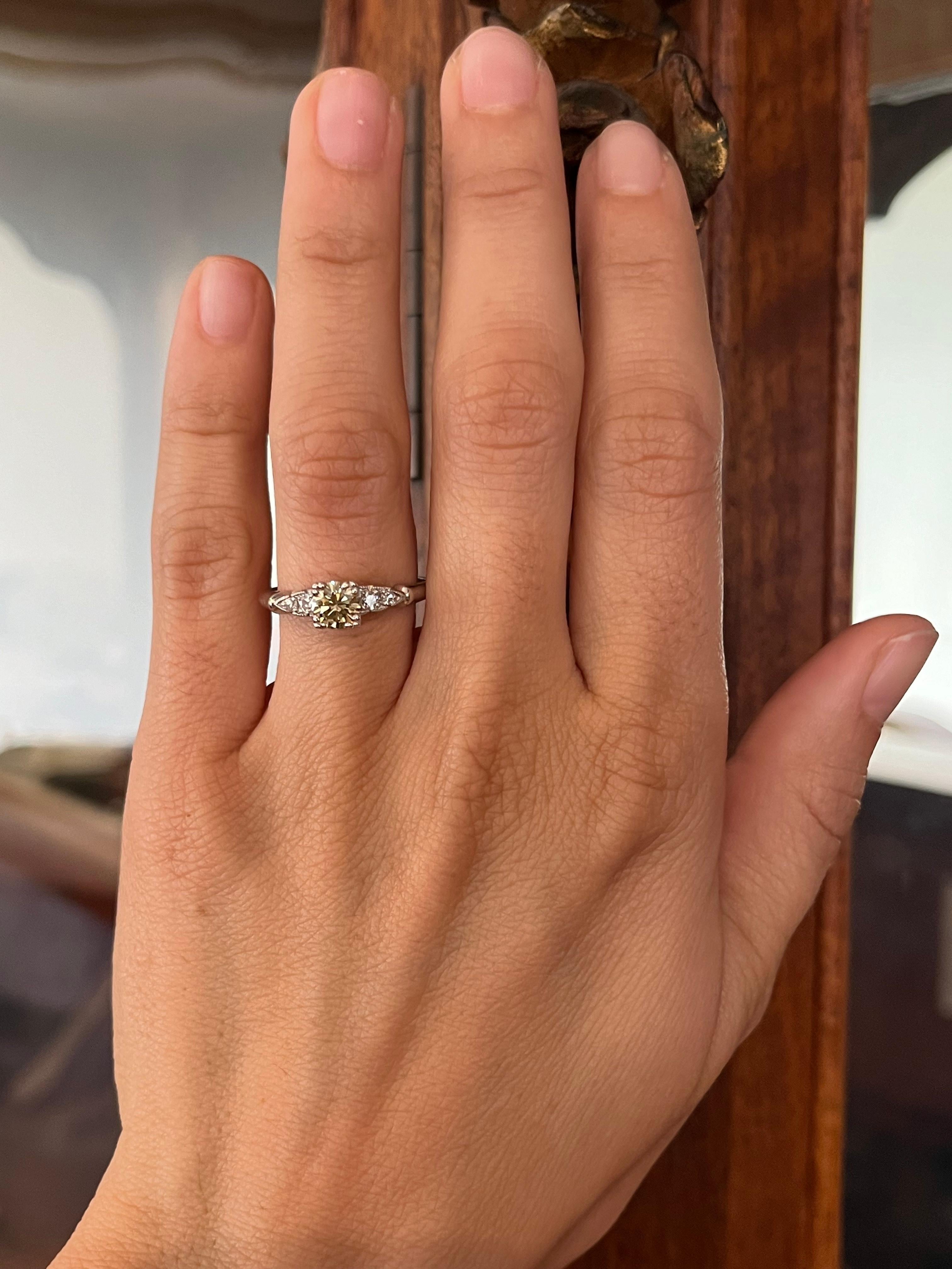 Circa 1950, cette bague de fiançailles en platine met en valeur un diamant jaune fantaisie naturel de 0,54ct avec une chaleur et une rareté d'époque. Encadrée par quatre diamants blancs étincelants, elle constitue un trésor unique du milieu du