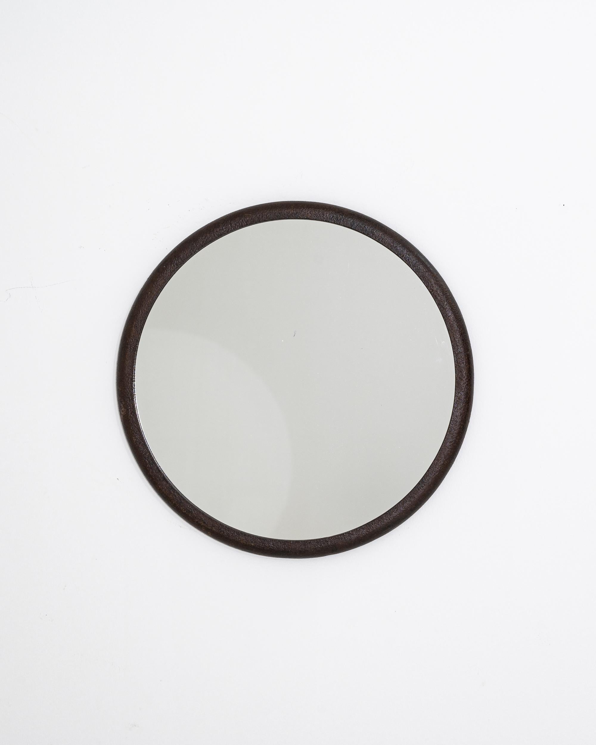 A polish iron mirror created in the 1950s. Simple yet elegant, this circular mirror offers unique Industrial charm. Its frame, a weathered and patinated metal ring adds a compelling grit to the materiality of the piece, standing in pleasing contrast