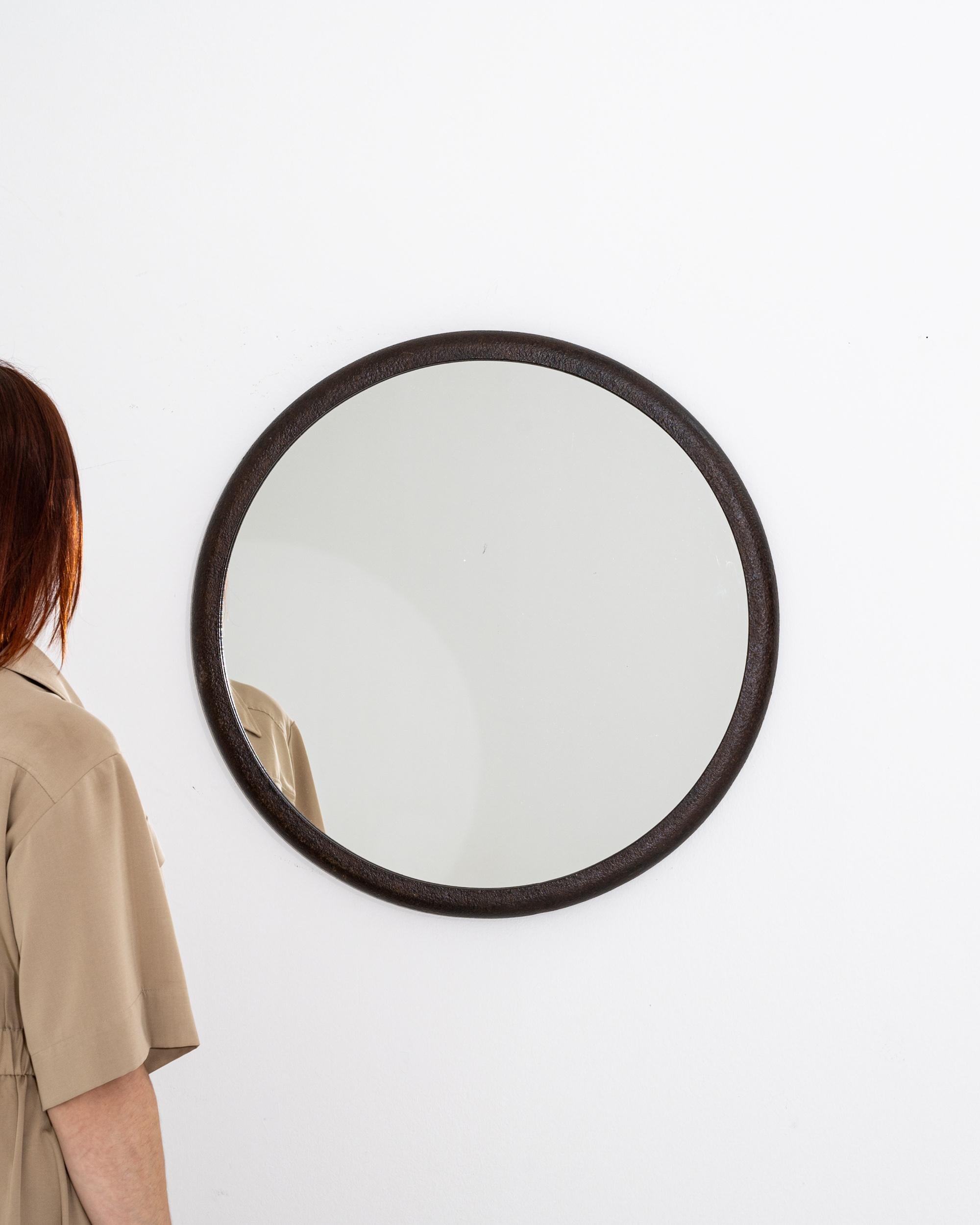 A polish iron mirror created in the 1950s. Simple yet elegant, this circular mirror offers unique Industrial charm. Its frame, a weathered and patinated metal ring adds a compelling grit to the materiality of the piece, standing in pleasing contrast