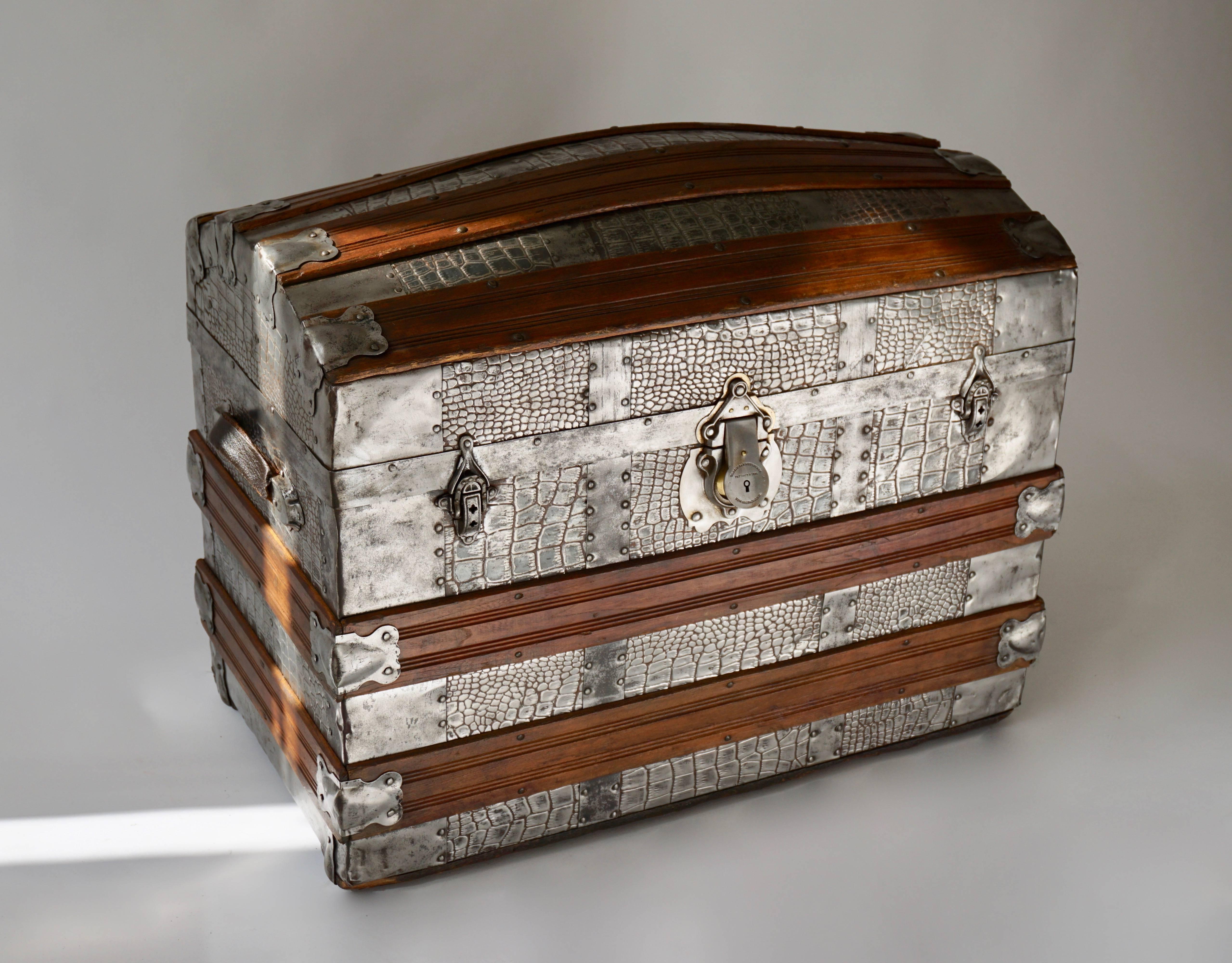 A highly unusual small size travelling trunk with fitted interior, the outside reinforced with studded metal crocodile skin pattern plates and secured with a patented Corbin Cabinet lock from the New Britain Company of Connecticut, USA. America,