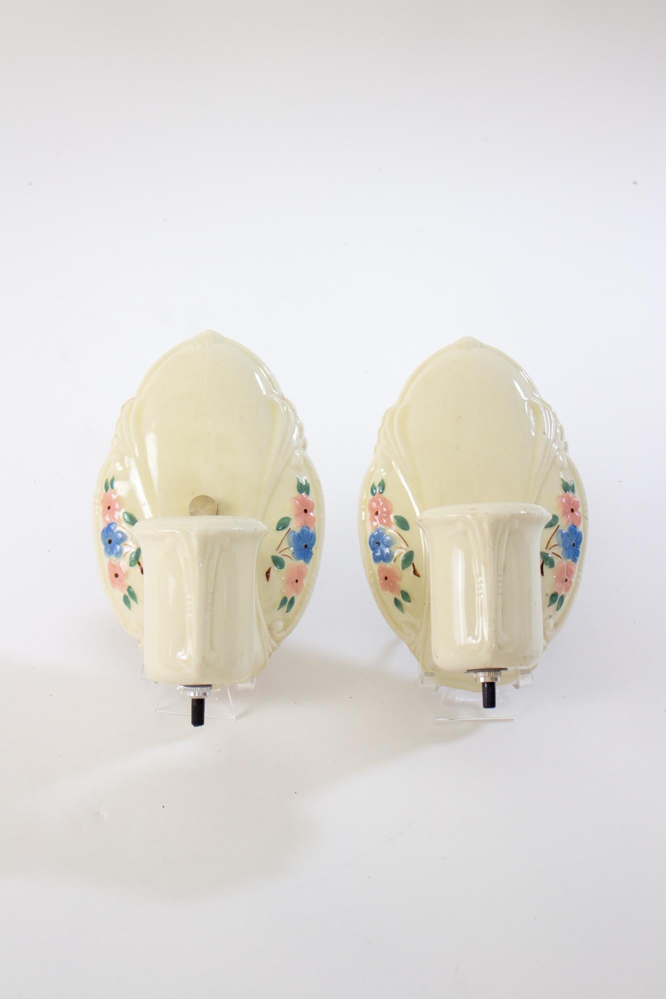 1950’s Porcelain Harmony House flowered sconces, a pair. Simple porcelain sconces. Ivory with blue and pink flowers. In good condition, rewired with new socket. Switch on bottom of socket. US 120V hardwired. 

Dimensions: 
Width: 4.5
