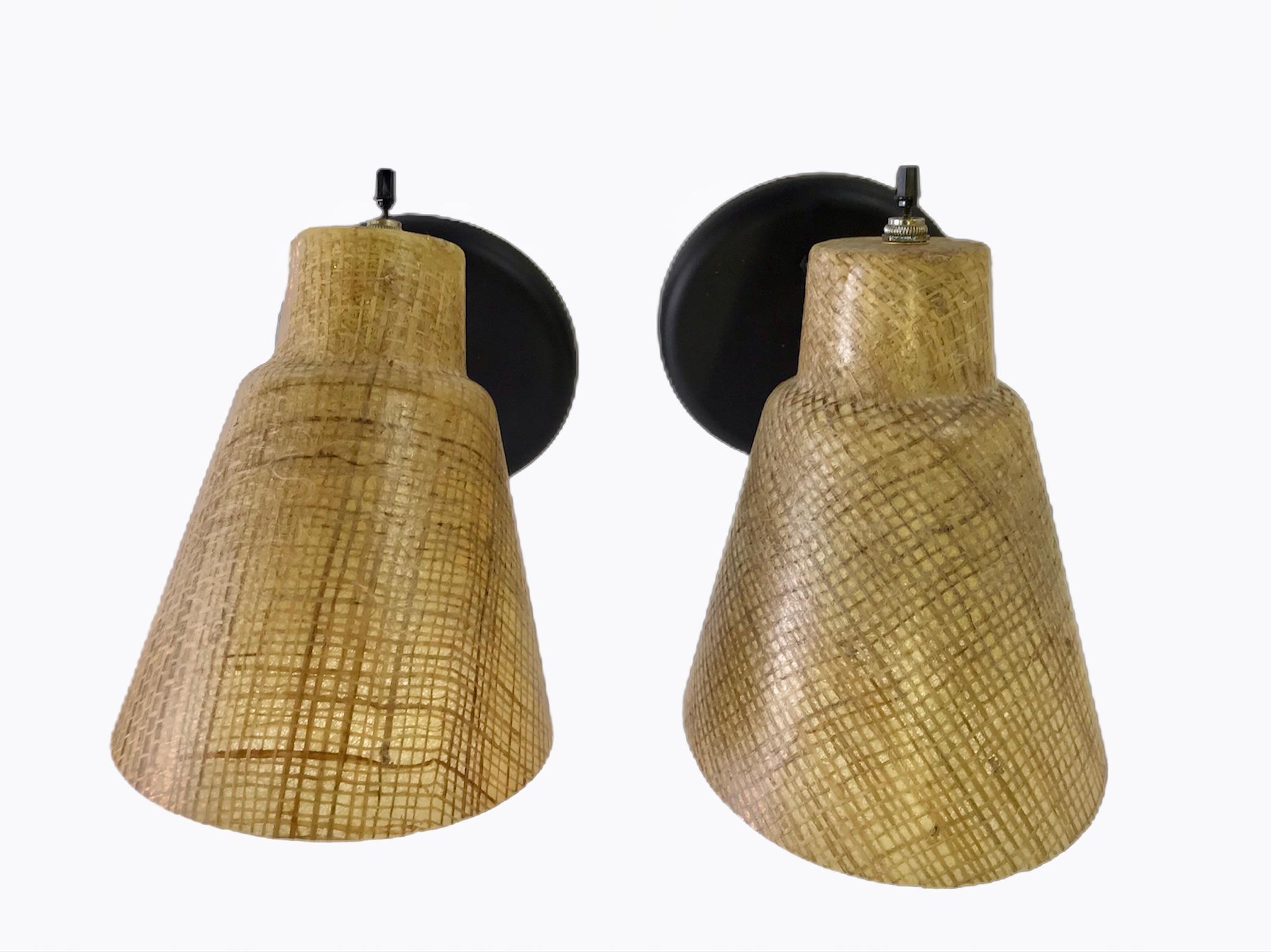 1950s styling in cone shaped sconces of acrylic encasing Raffia. Fully adjustable, they have been rewired and have new black wall plates and turn toggle switches on top.

Measurements: Shade 7 1/2 inches long x 5 1/2 inch opening.
