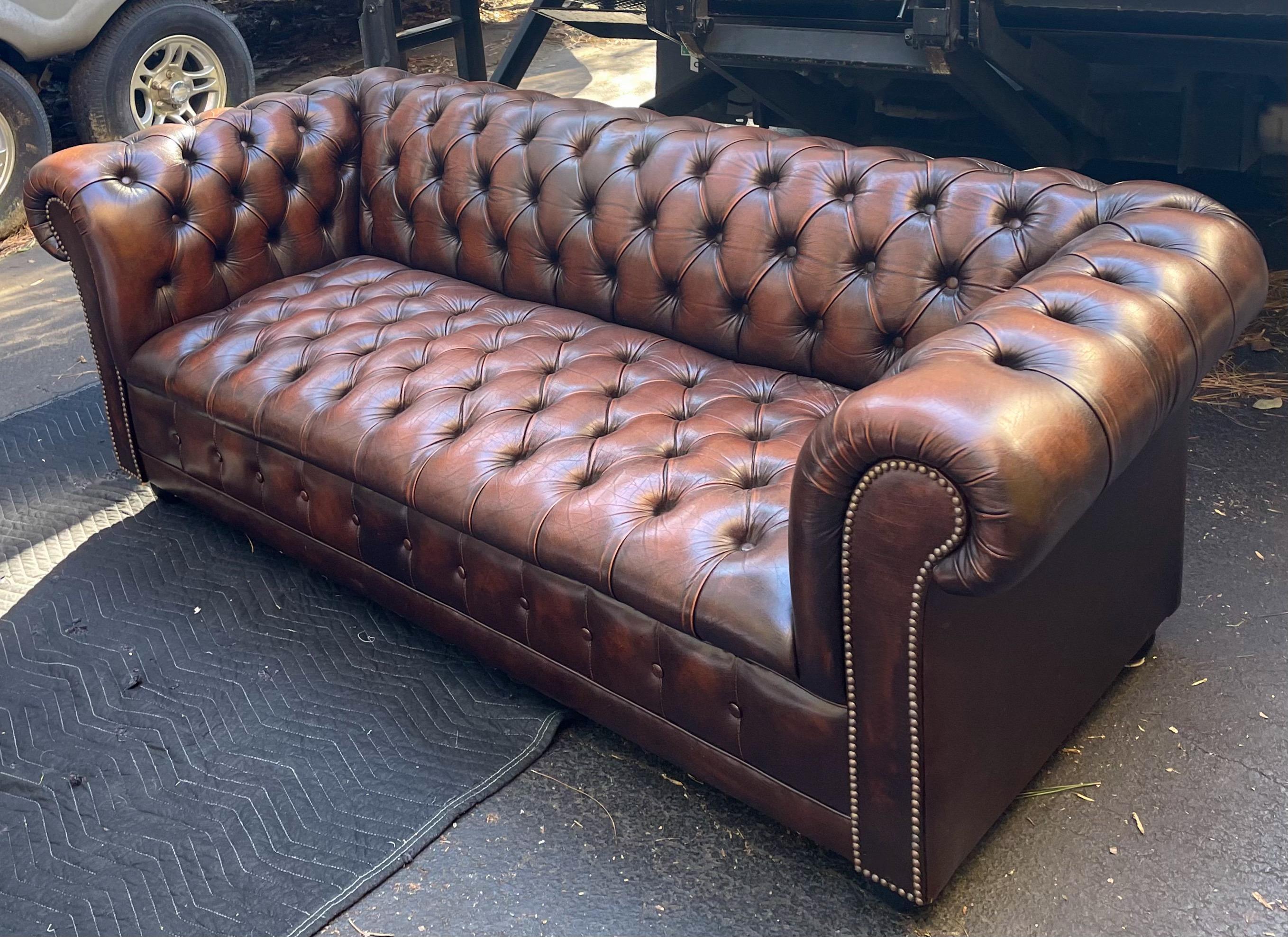 This is wonderful! This is a timeless piece that works with a variety of design projects! This is a 1950s English tufted brown leather sofa with bun feet. It has some general patina enhancing wear.