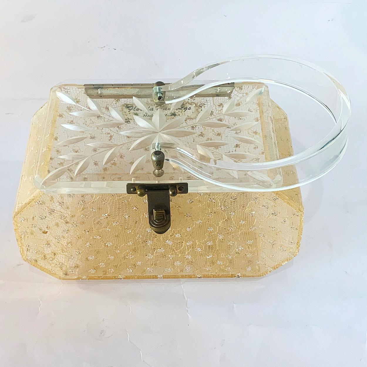Mid Century Florida Handbag in the palest pink with “Gilt sparkles” in diagonals, within the Lace, set to Lucite, and a Carved, Diamond Leaf Carved, clear Lucite Lid and horseshoe shaped swing handle on perfect bronze domed posts, with bronze pins