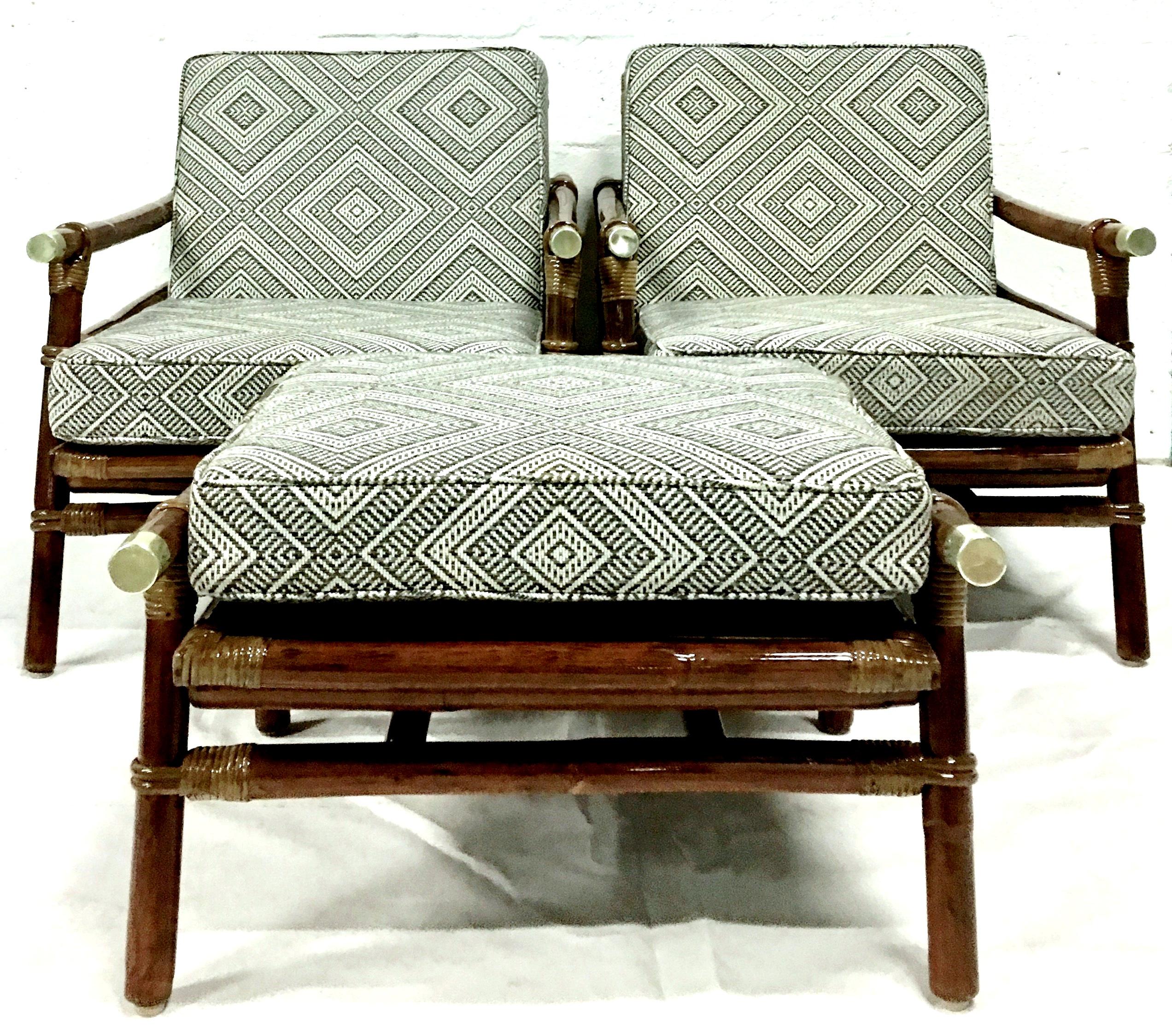 1950s newly restored Campaign style rattan, raffia and brass pair of lounge armchairs and ottoman by John Wisner for Ficks Reed., Set of three. Includes custom fabricated (2011) indoor-outdoor set of five cushions. The hardwood and rattan frame with